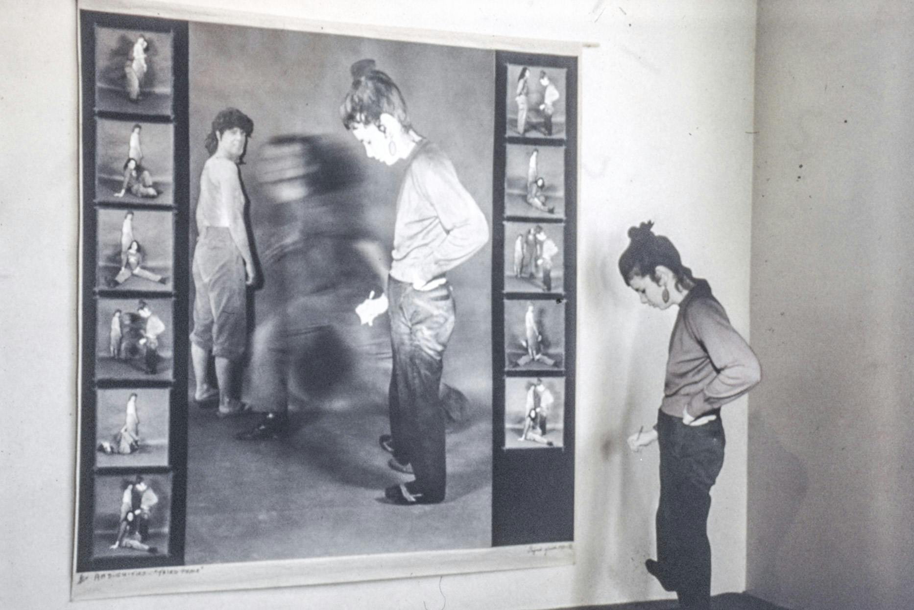 A life-size photo, and several smaller ones, of a person running between two cardboard cutouts of people mounted on a wall.  One of the cutouts is placed on the wall beside the photo.