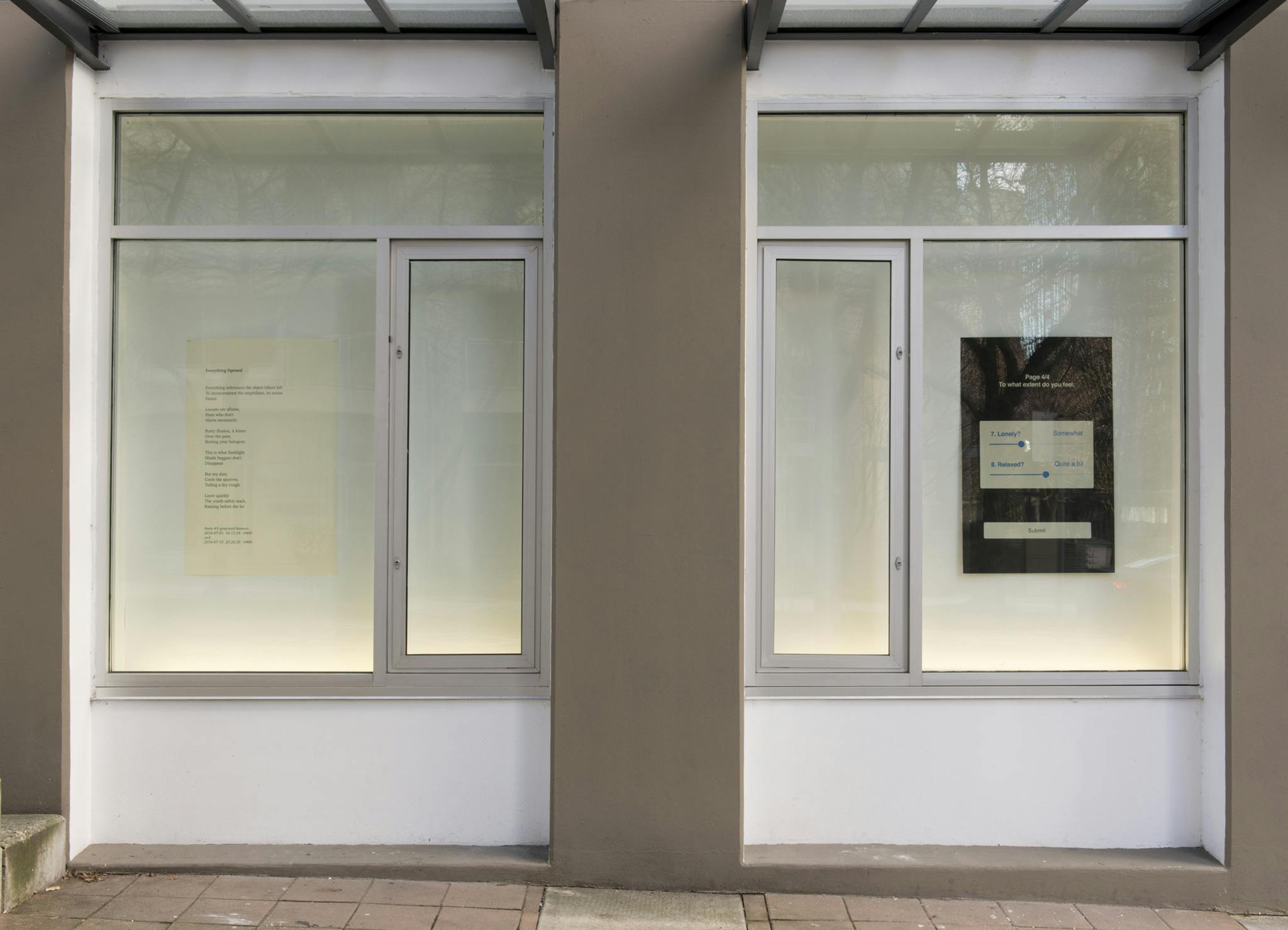 Two windows outside of CAG installed with a text-based print each. One print has a poem printed in black text on white paper. The other has a poem printed in white text on back paper.