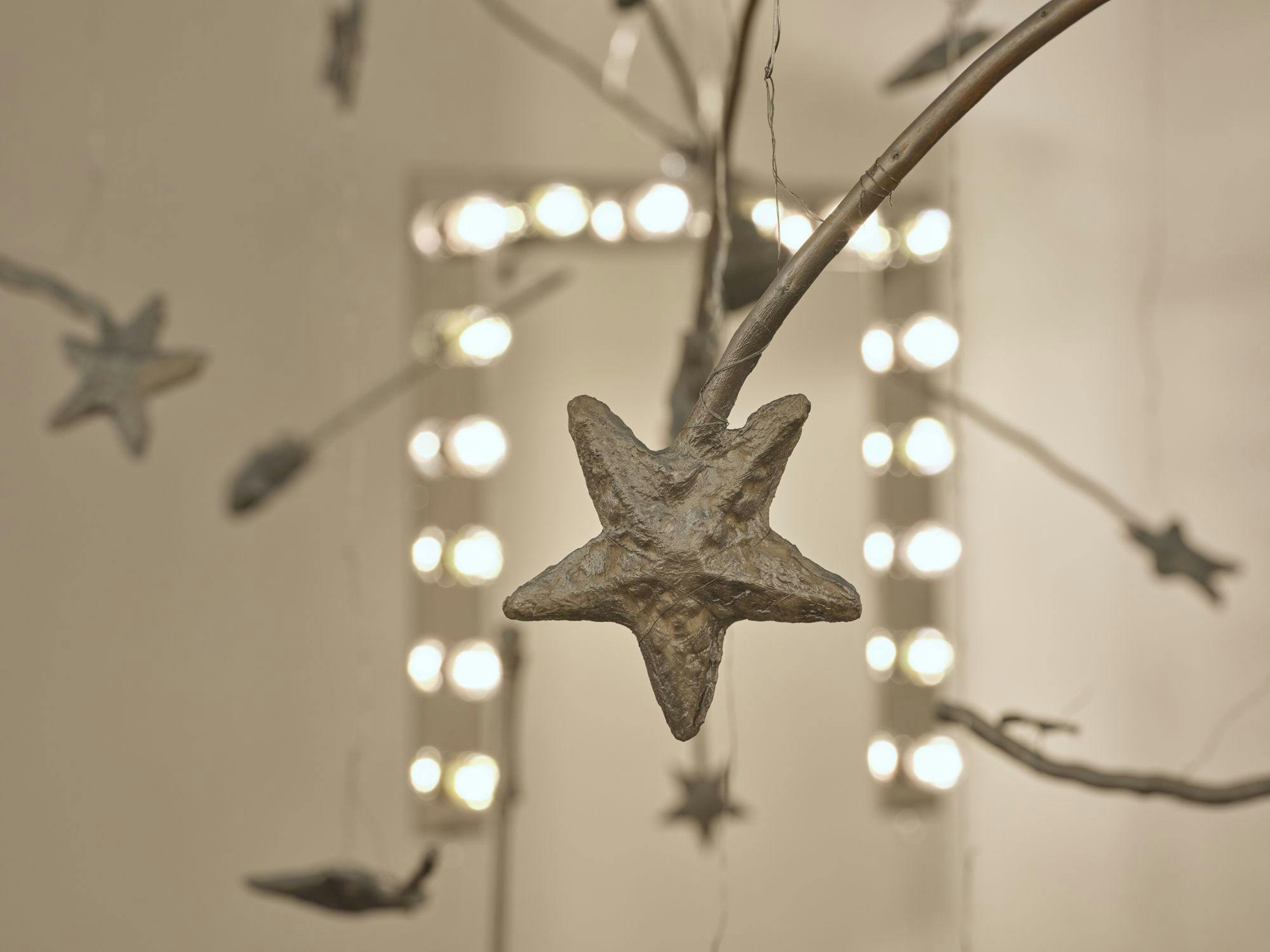 A detail view of a silver magic wand. In the background are a vanity light and more magic wands hanging from wire.