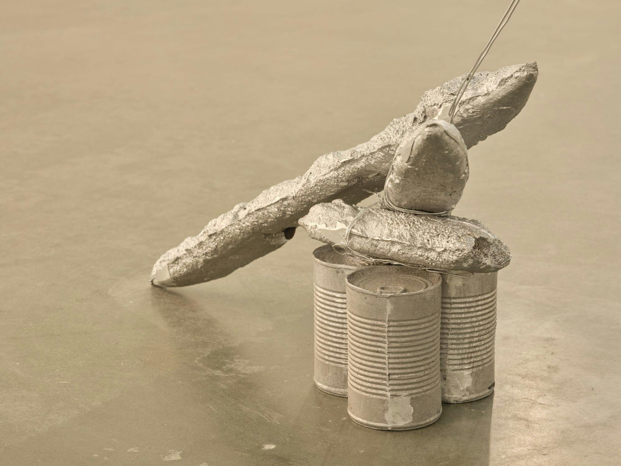 A detail of a sculpture comprised of silver-painted baguettes, wire, and aluminum cans.