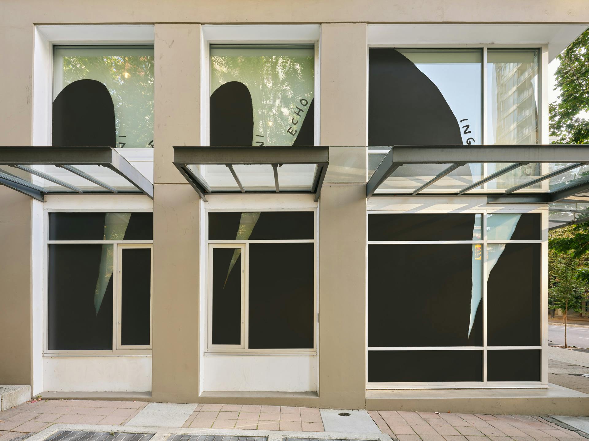 Facade of CAG with with two rows of windows visible in frame. Black and white drawings by Christine Sun Kim featuring the word "echoing" across the windows.