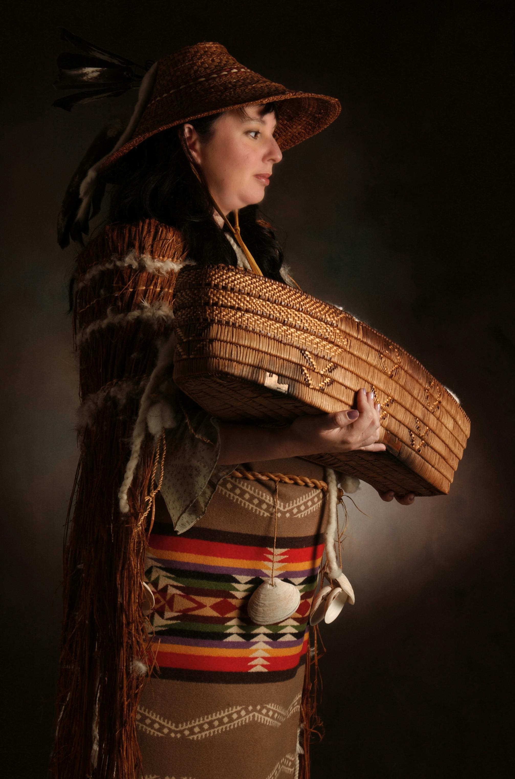 Sesemiya in profile holding a woven basket.