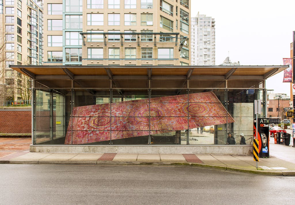 Installed on the facade of Yaletown-Roundhouse Station is a photograph in vinyl of a large rectangular carpet. The image is reproduced at a slanted angle, making the carpet look like it is flying.