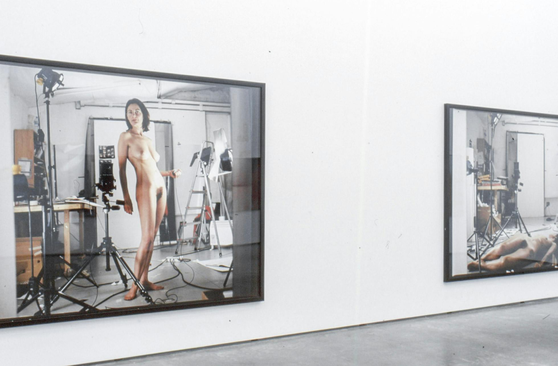 Several large-sized photographs are installed on a gallery wall. Those photographs show a naked woman posing in the middle of an artist studio.
