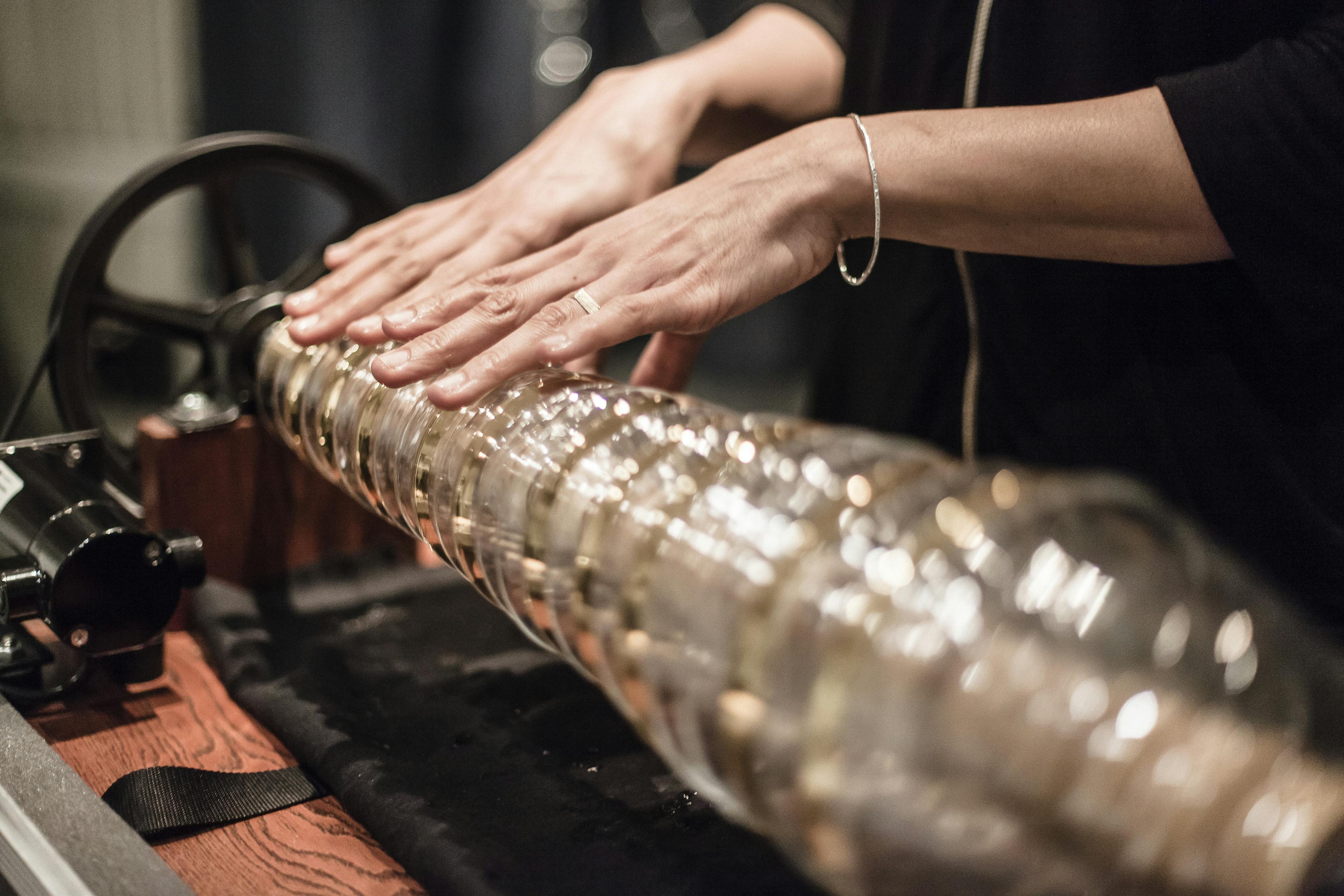 Image of a pair of hands placed on a glass armonica. 
