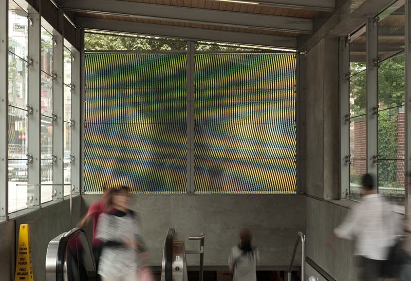 Nicolas Sassoon’s Moiré-patterned mural installed on the windows of Yaletown-Roundhouse station. Black and rainbow-coloured pixels overlap with each other to create a Moiré pattern of undulating waves.