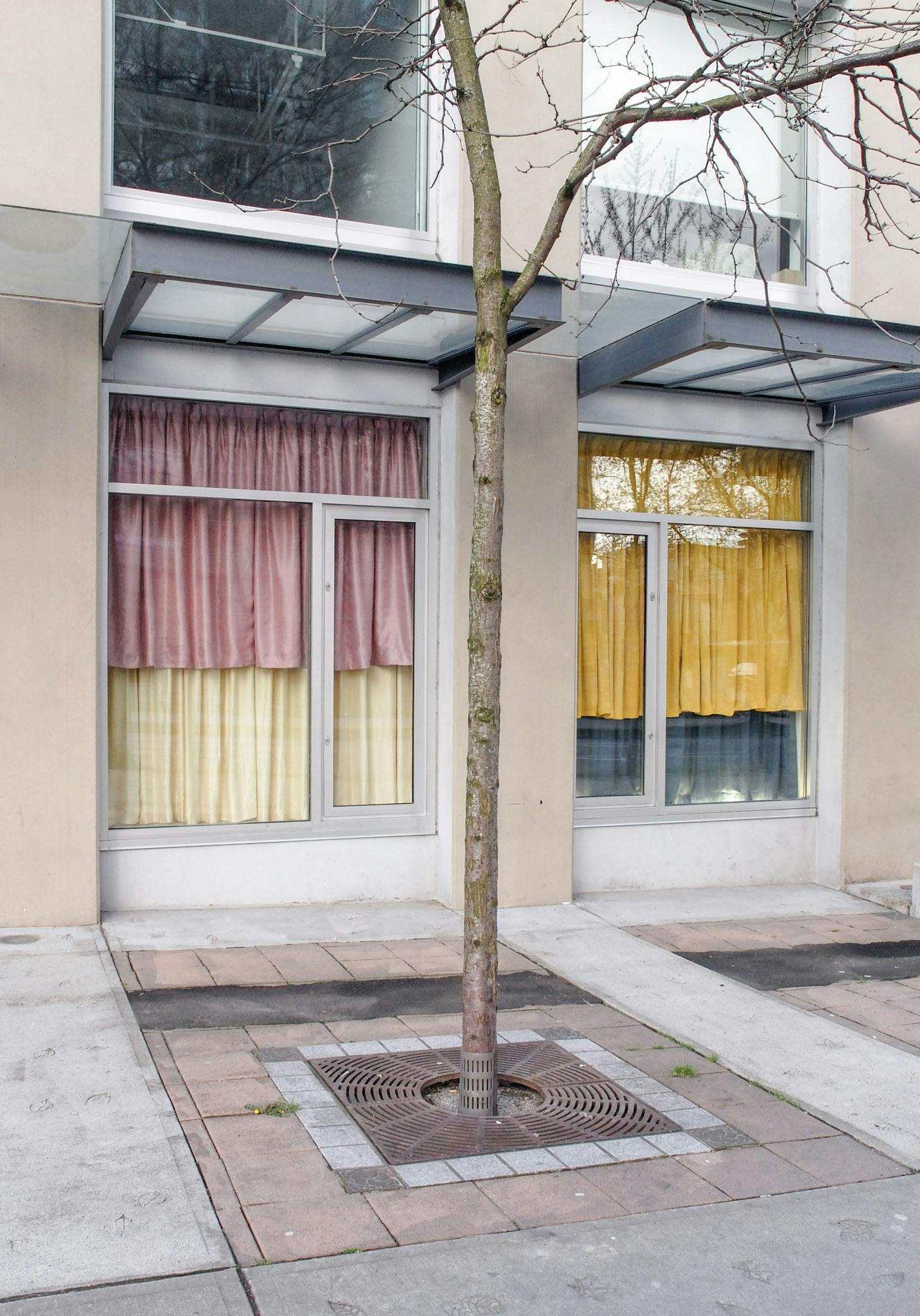 CAG’s window spaces are covered by the fabric installation by Derek Brunen. Two of those windows visible in this image are covered with pink, yellow and dark blue curtains. 