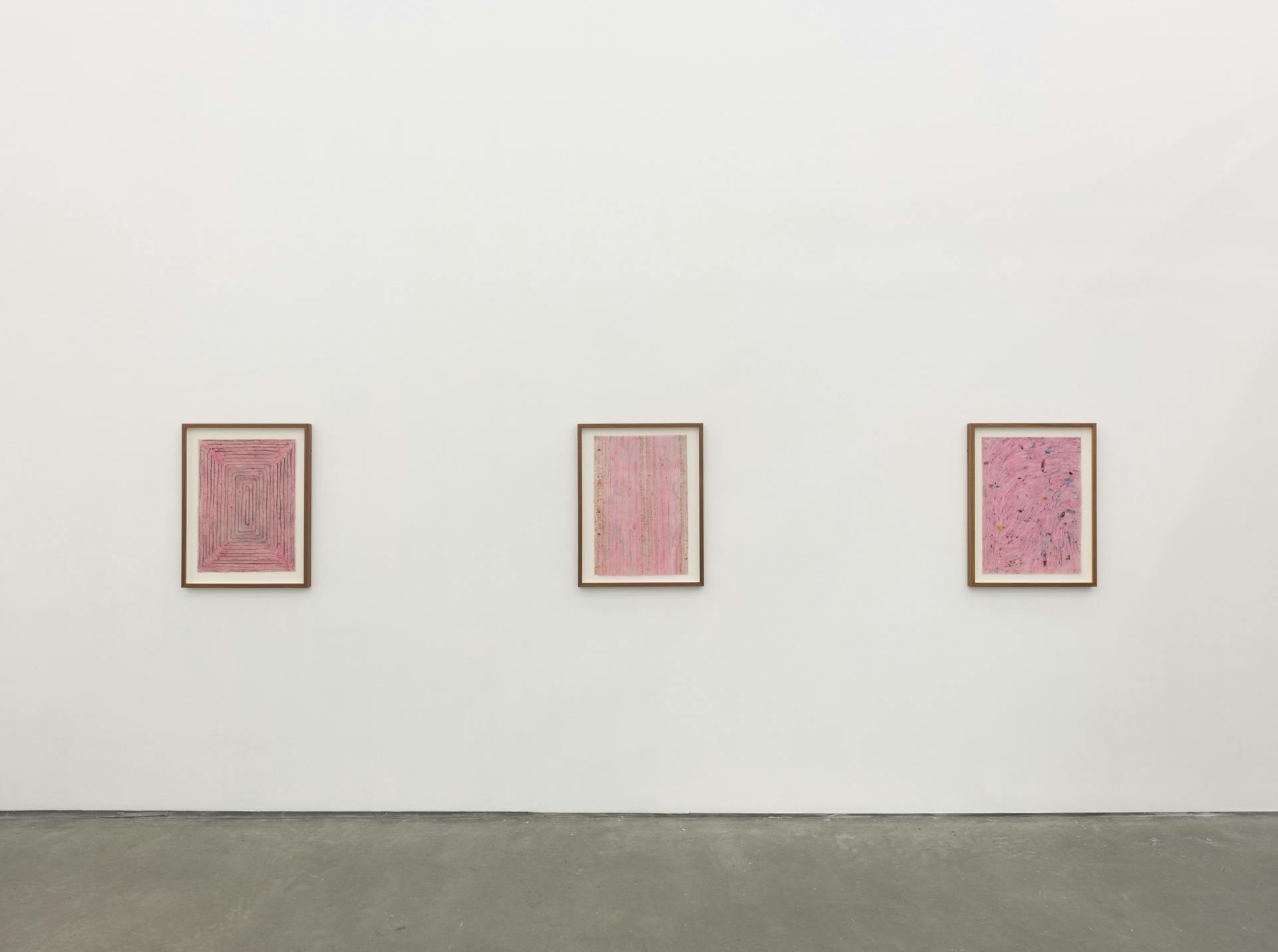 Three framed pink collages on a white wall.