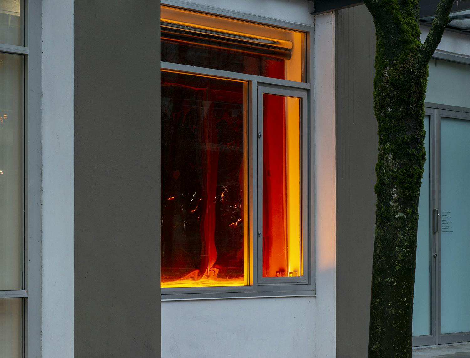 Detail shot of the exterior of the Contemporary Art Gallery displaying the work of Nicole Kelly Westman in a window. One window on the first floor is lit from the bottom displaying a red backdrop.