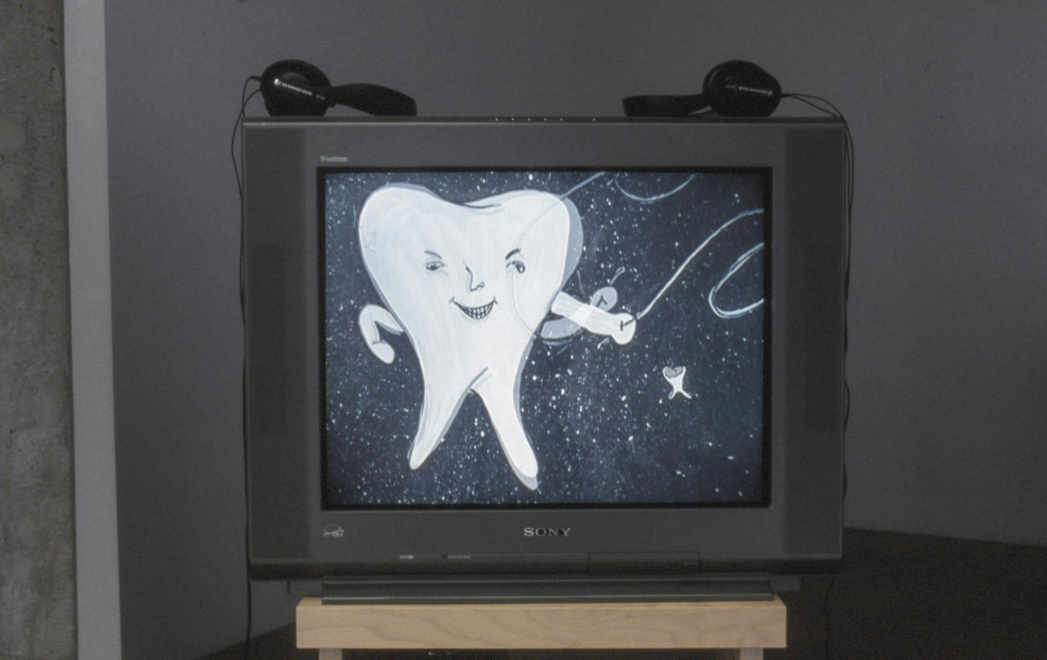 Detail of a video installation by Marina Roy. A CRT TV shows a black and white illustration of a character, whose body looks like a tooth fallen off, standing in a dark background filled with stars.