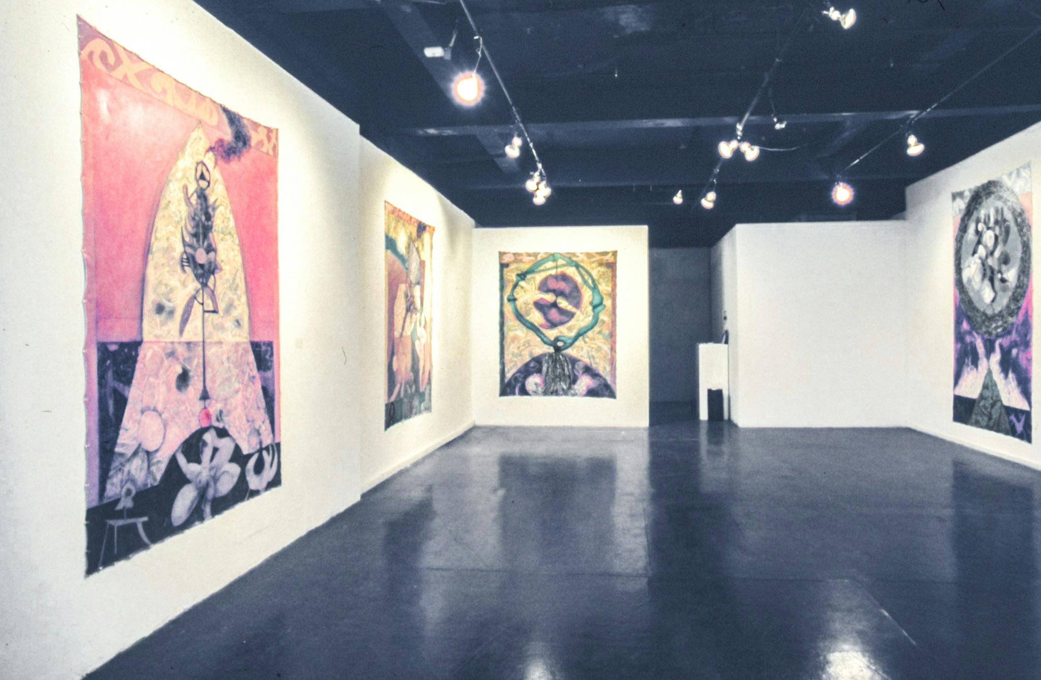 Several large, colourful paintings are pinned onto the walls of a gallery. The paintings show complex patterns and abstracted images, some resembling hands, flowers, and insects. 