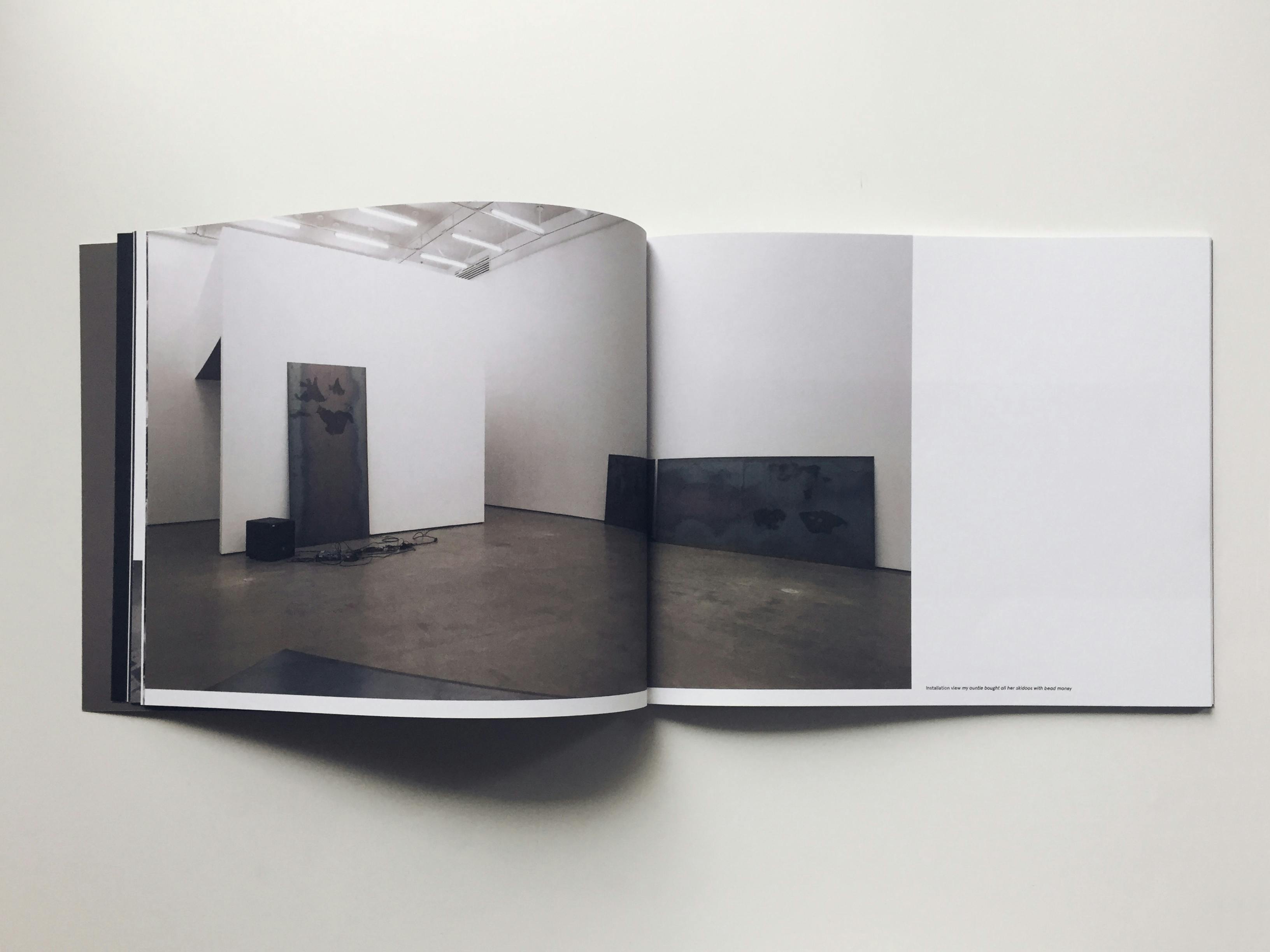 An open page from Jeneen Frei Njootli's monograph, titled "my auntie bought all her skidoos with bead money." The installation image of the same-named exhibition, where the artist placed large sheets of steel in the gallery, is printed on the page. 