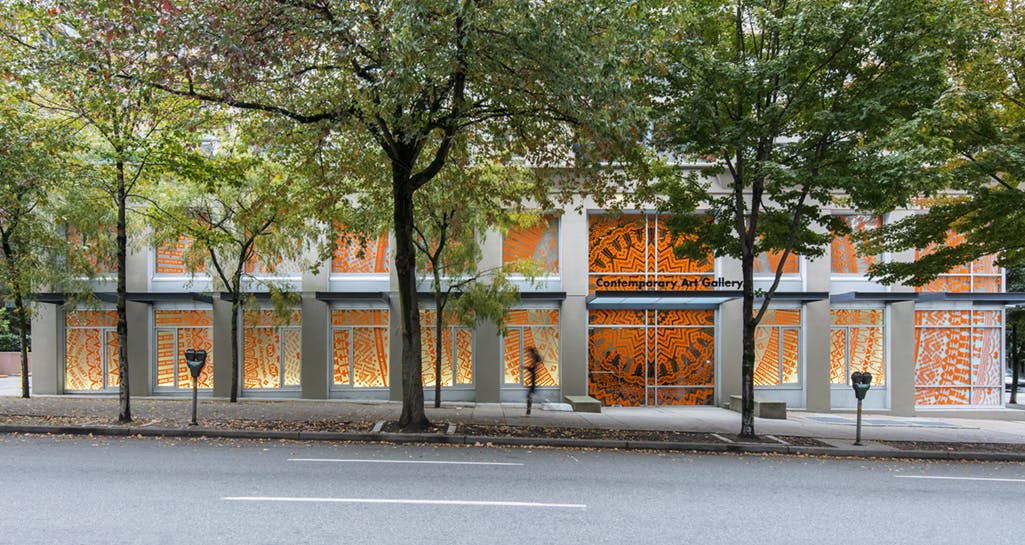 Exterior image of CAG’s facade, with all of the windows installed with Gunilla Klingberg’s work. A dark orange pattern in cut vinyl covers the windows on both floors. 