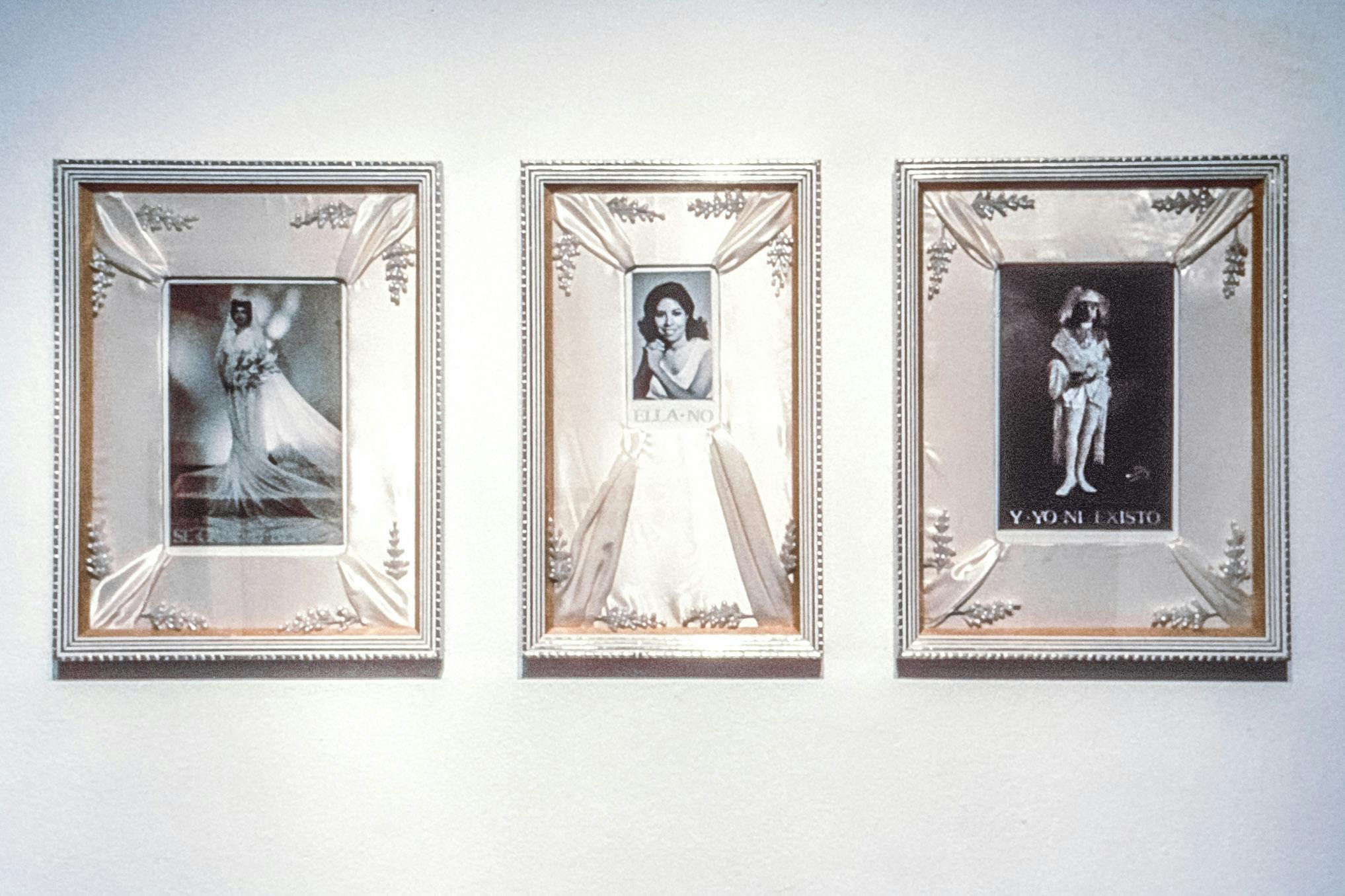 A series of three art pieces are mounted on a gallery wall. They are identically framed in silver, and in the middle each has black and white portrait photograph of a person. 
