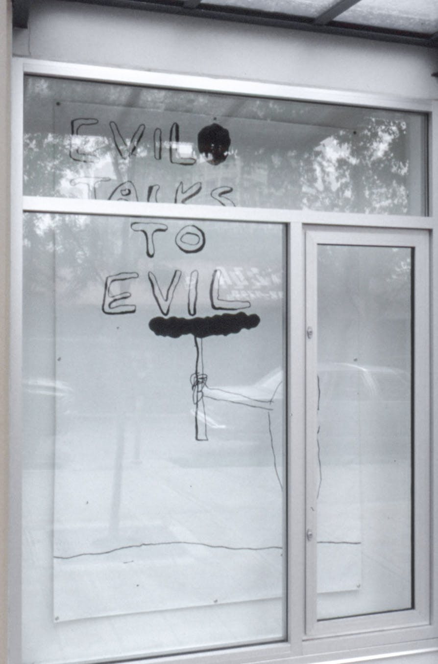 Jill Henderson’s drawing is installed in one of CAG’s window spaces. The window in this image showcases a handwritten text that reads “evil talks to evil” all in upper cases. 