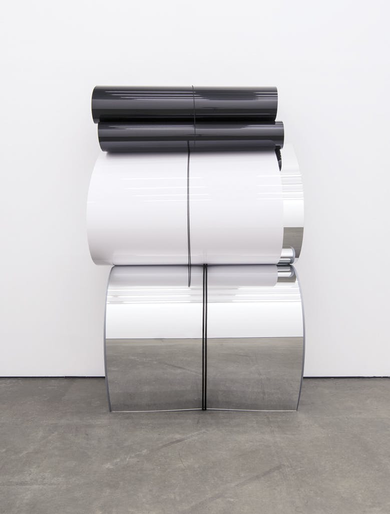 A sculpture made of large, arched and bent sheets of reflective material stacked atop one another. 