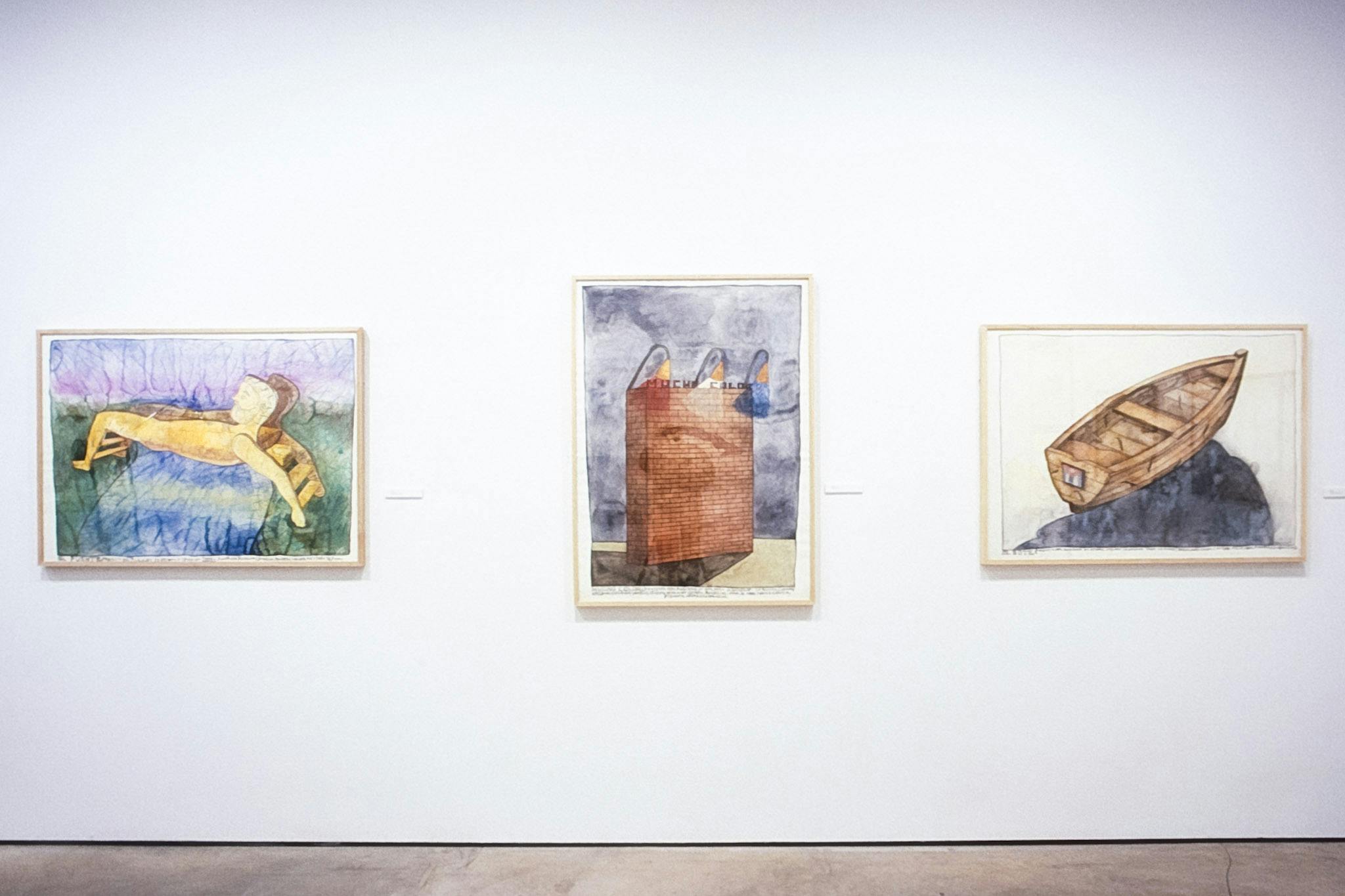 Three colored drawings are installed on the gallery wall. The left one shows a human body bridging over the river, and the middle one depicts a brick wall. The one on the right depicts a wooden boat.