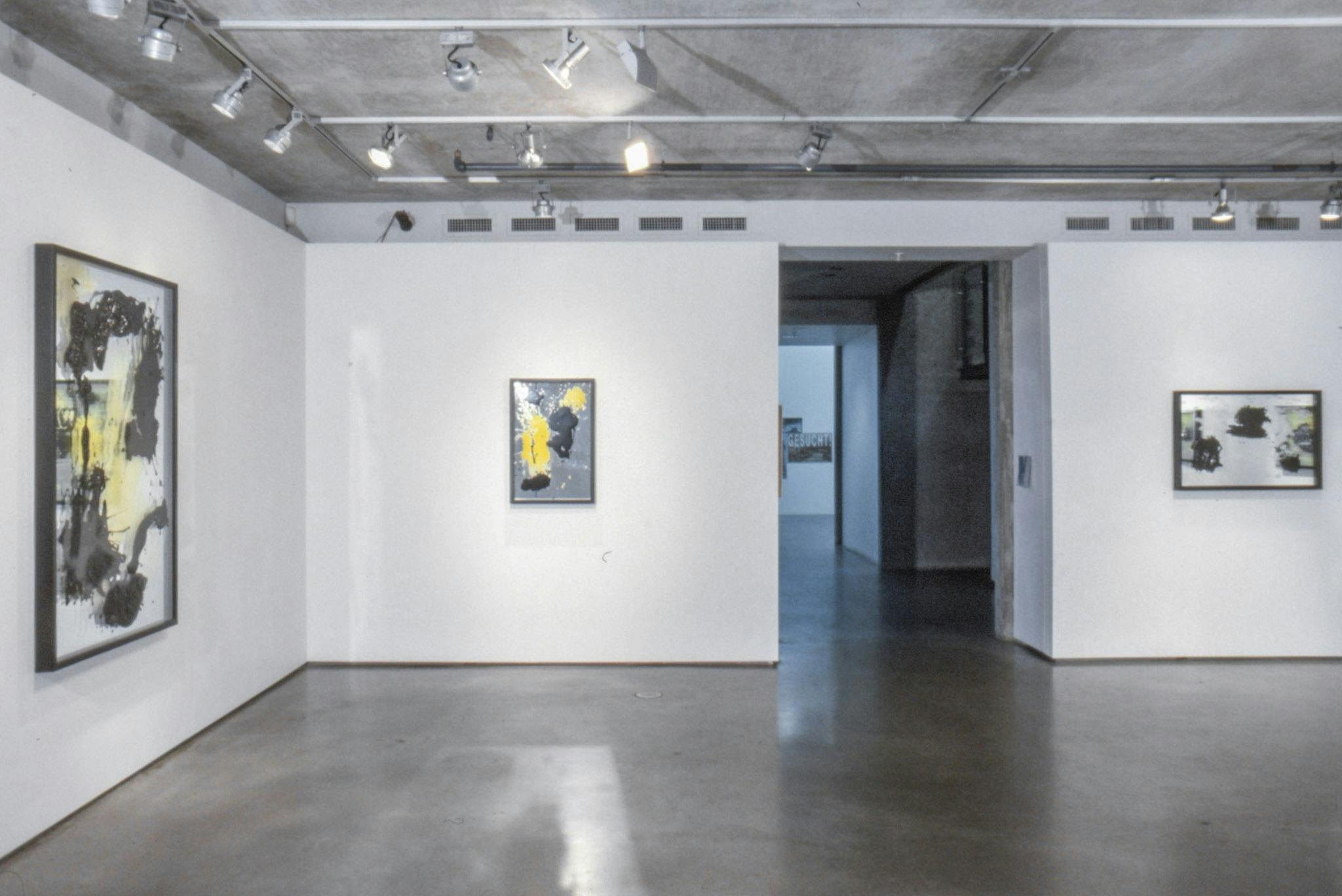 Installation image of Marina Roy’s paintings. Paintings of abstract shapes in black and yellow are made on the mirrors. Three paintings, varying in size, are mounted on the walls.