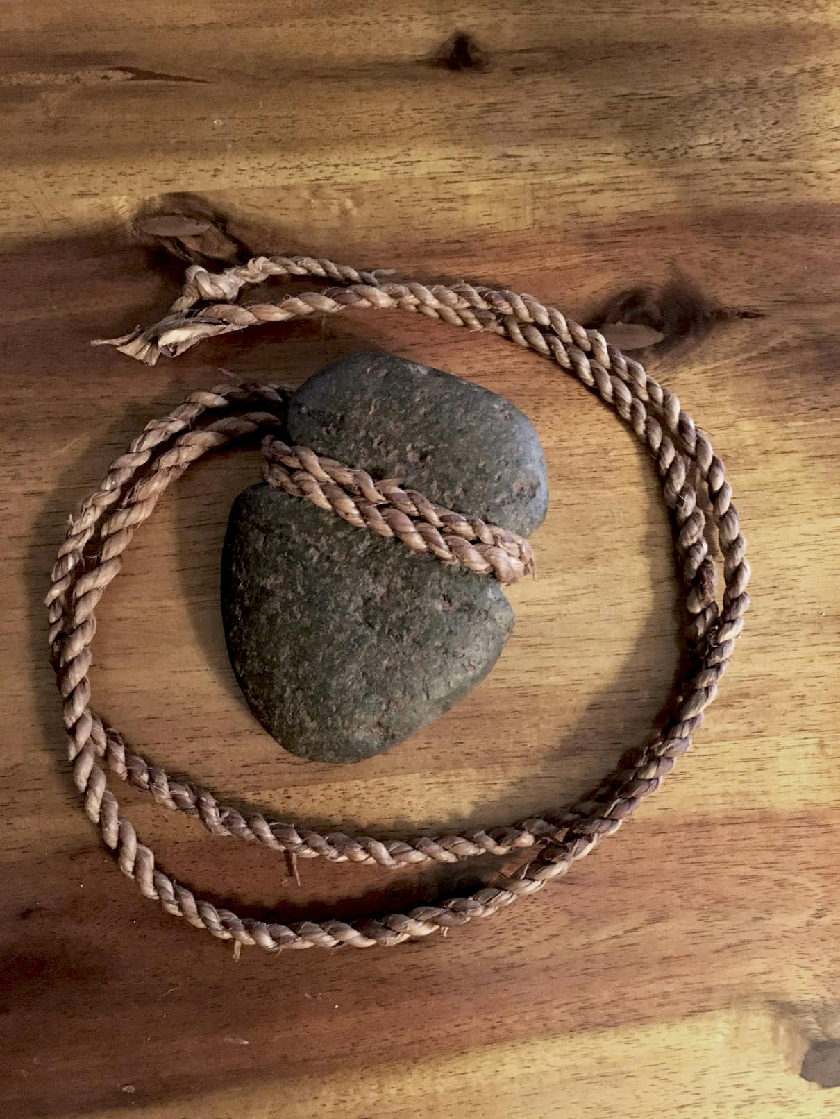 A carved stone wrapped with a rope displayed on a wooden surface.