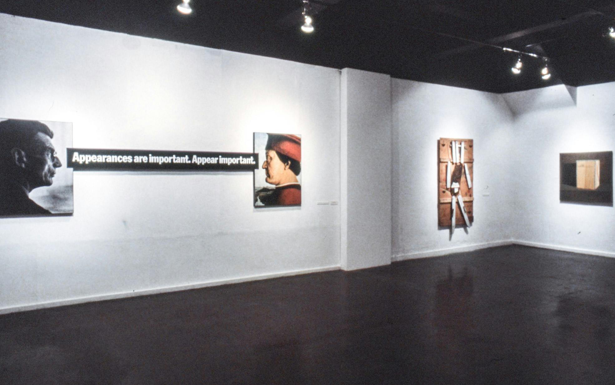 3 artworks in a gallery. One work is made of 2 portraits facing each other, and text between them reads "Appearances are important. Appear important." The other 2 works are a sculpture and a painting. 