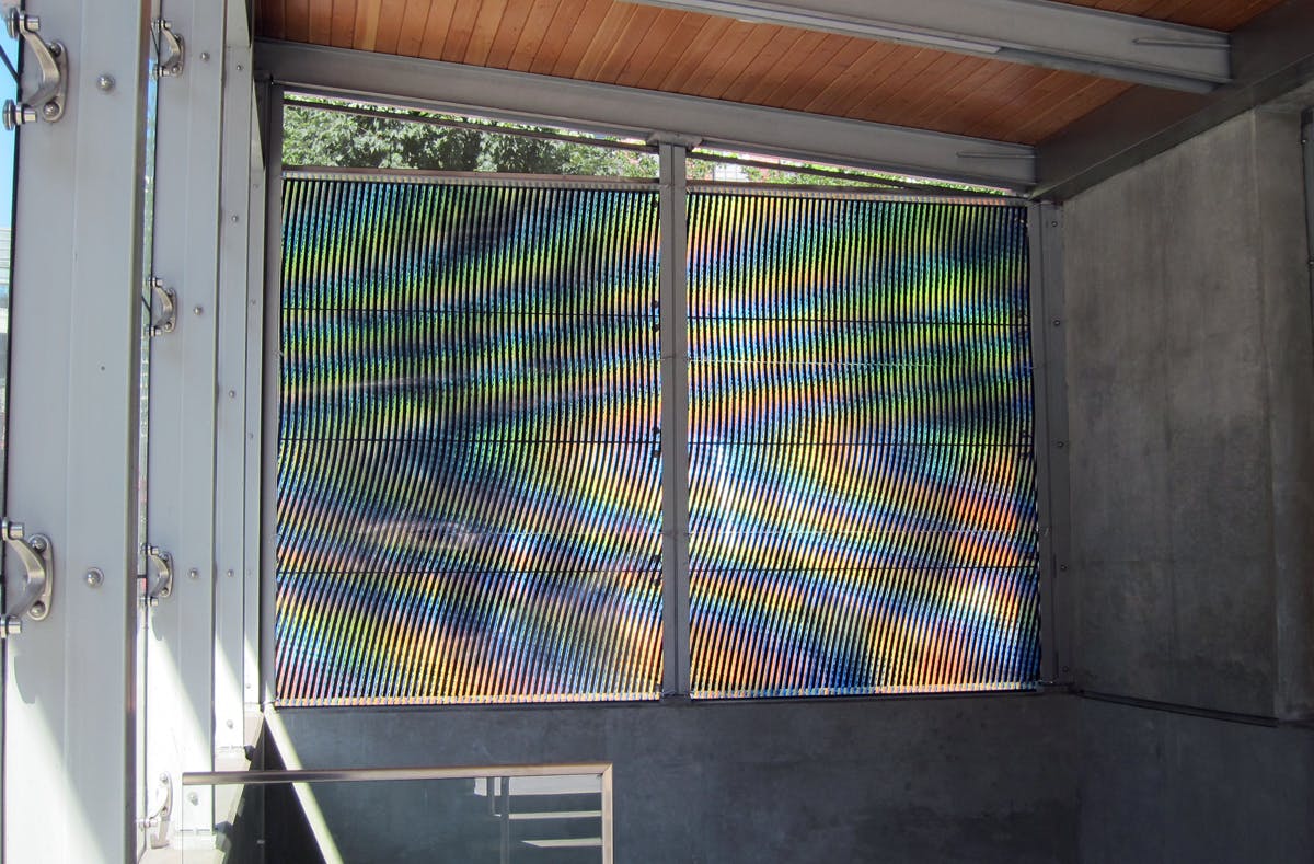 Nicolas Sassoon’s Moiré-patterned mural installed on the windows of Yaletown-Roundhouse station. Black lines of pixels atop a pixelated, coloured background form a rainbow pattern of undulating waves.