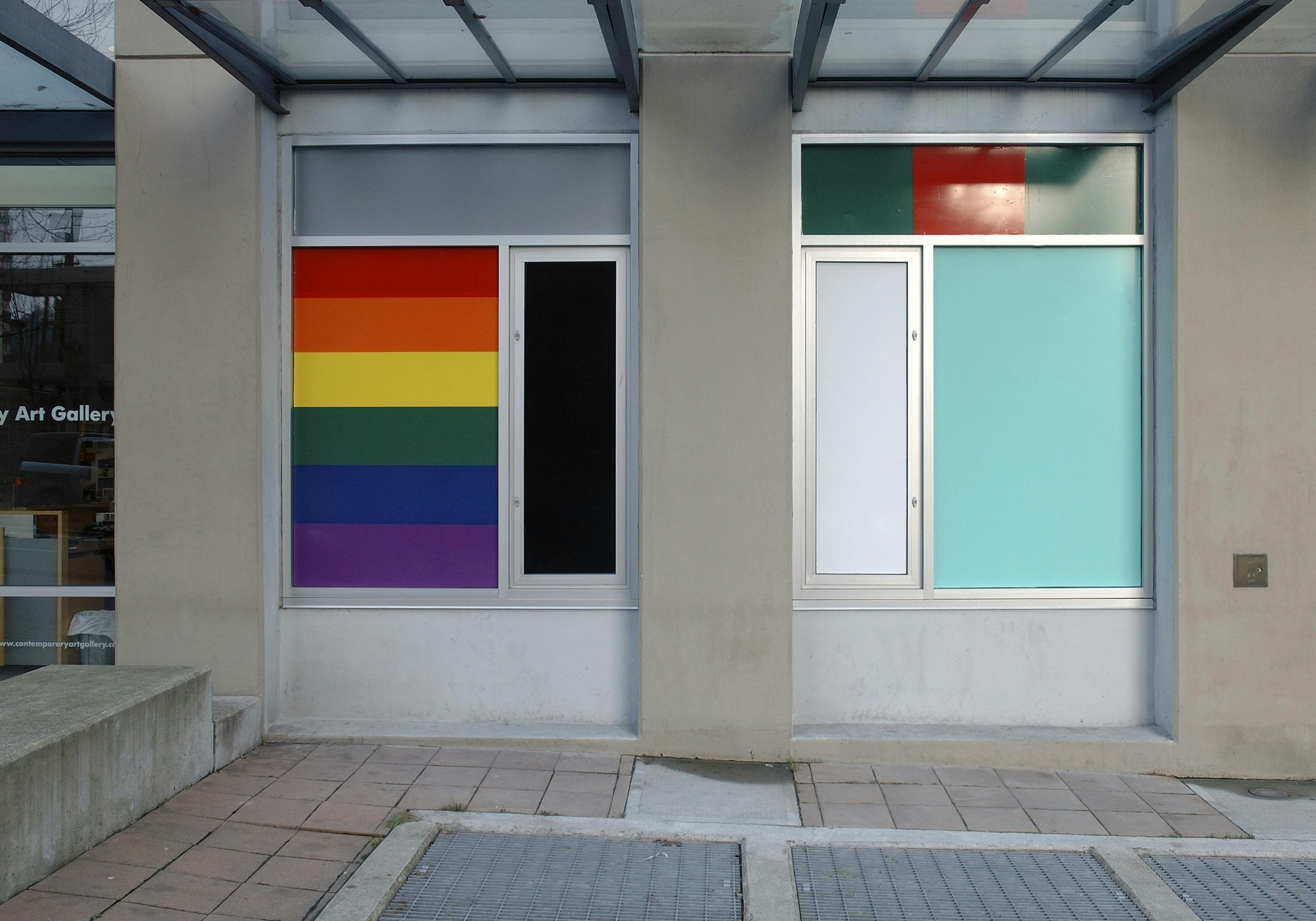 Install image of the first floor windows of CAG facing Nelson Street. Vinyl sheets cover entire windows. One window is covered with a seven-striped rainbow flag pattern. 
