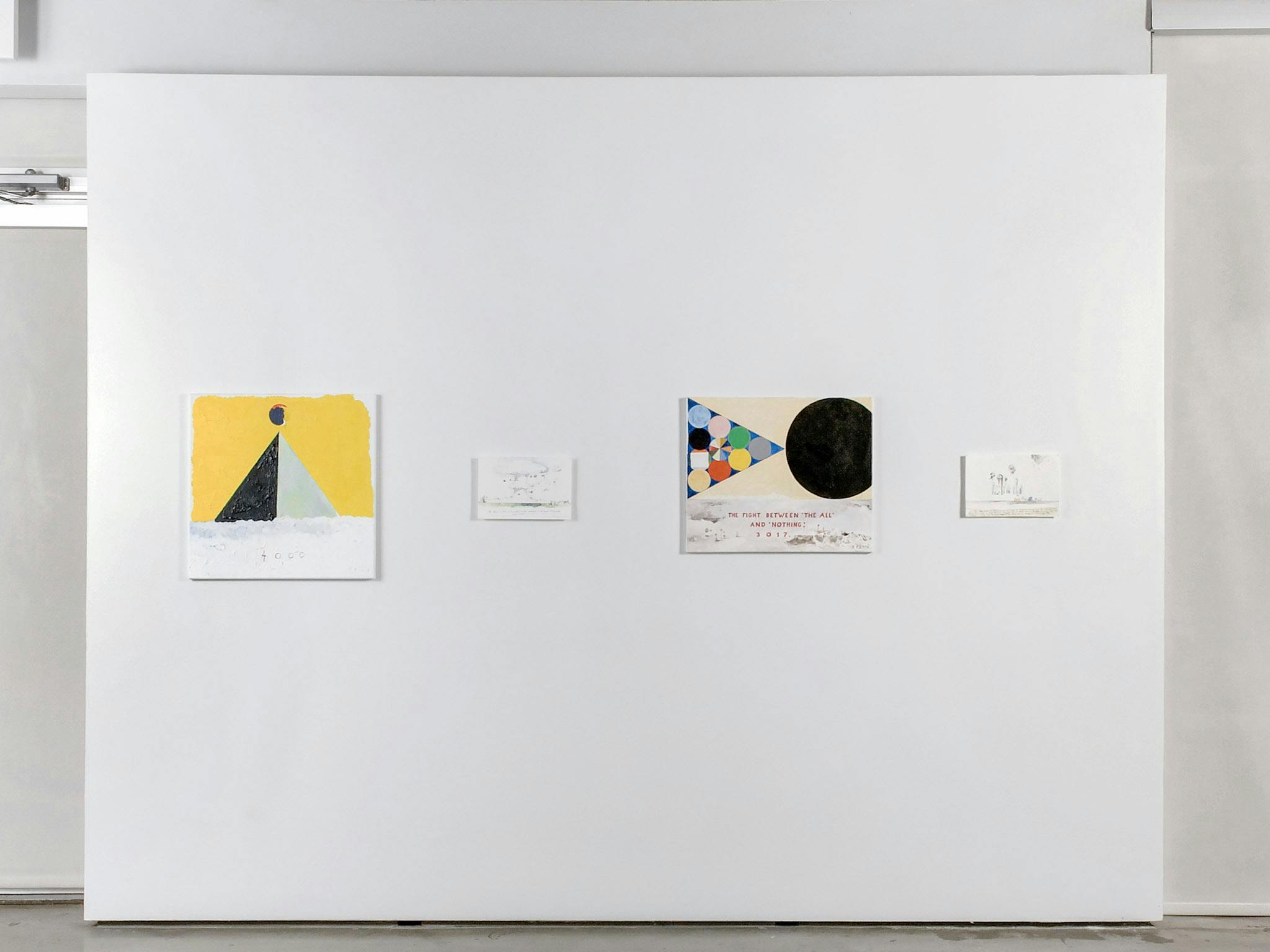 Four coloured drawings are mounted on the gallery wall. Two of them are larger than the rest. These large drawings depict geometric shapes including triangles and circles. 