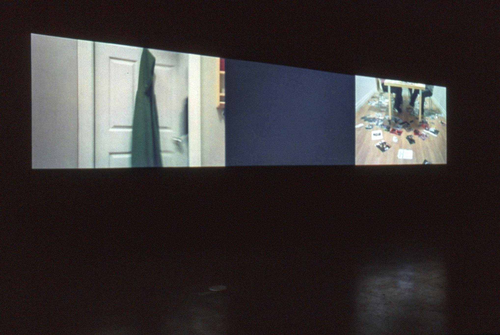 Installation image of a three-channel video by Alex Morrison. The middle video only shows a black screen. Two other videos show some images taken inside houses, including table chairs and a door. 