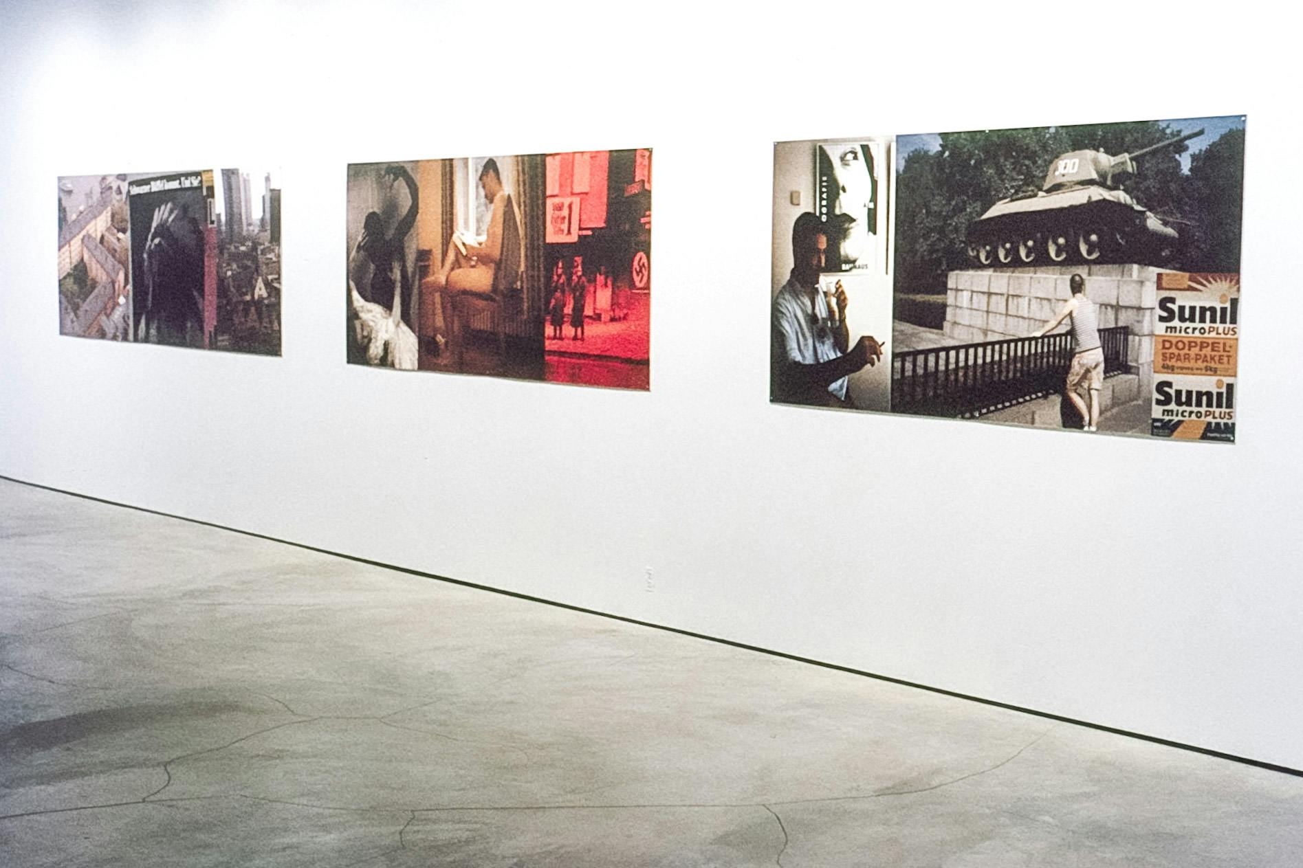 Three large horizontal works on a gallery space. The pieces have 2 or 3 photos included in each. The photos include a birds-eye view of a building, a naked person reading, and a person smoking. 