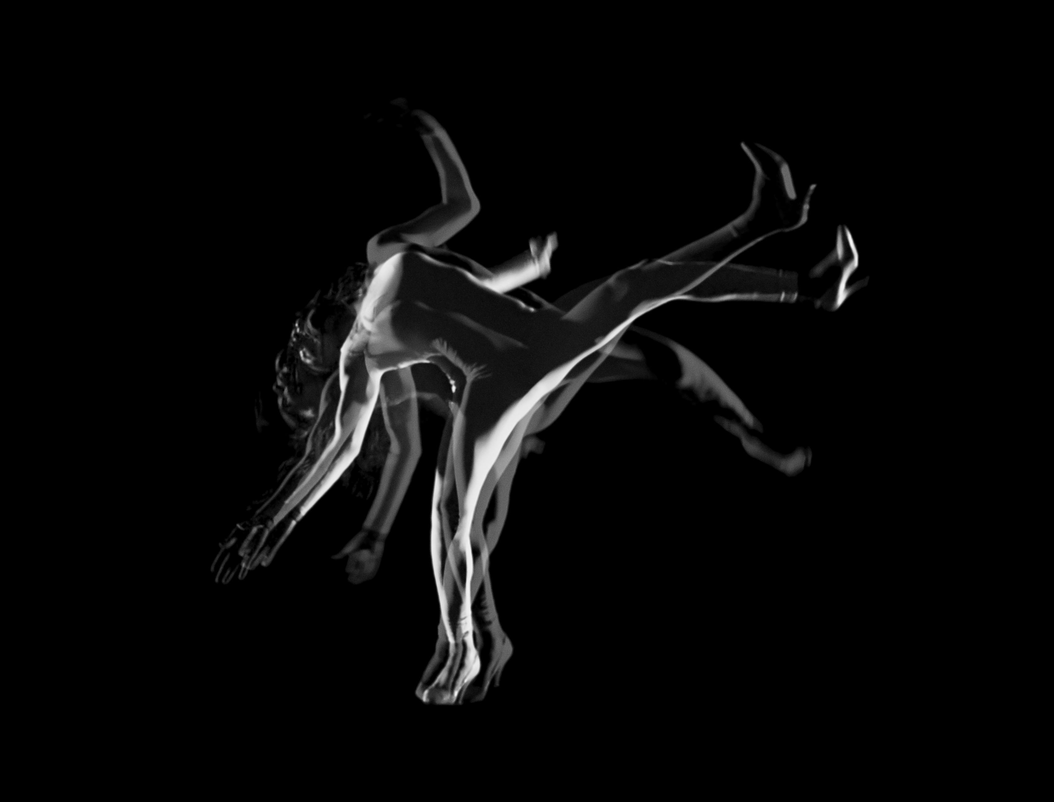 A black and white image of a starkly lit dancer in motion wearing a white unitard. Multiple translucent images of the dancer in slightly varying positions are overlaid against a black background. 