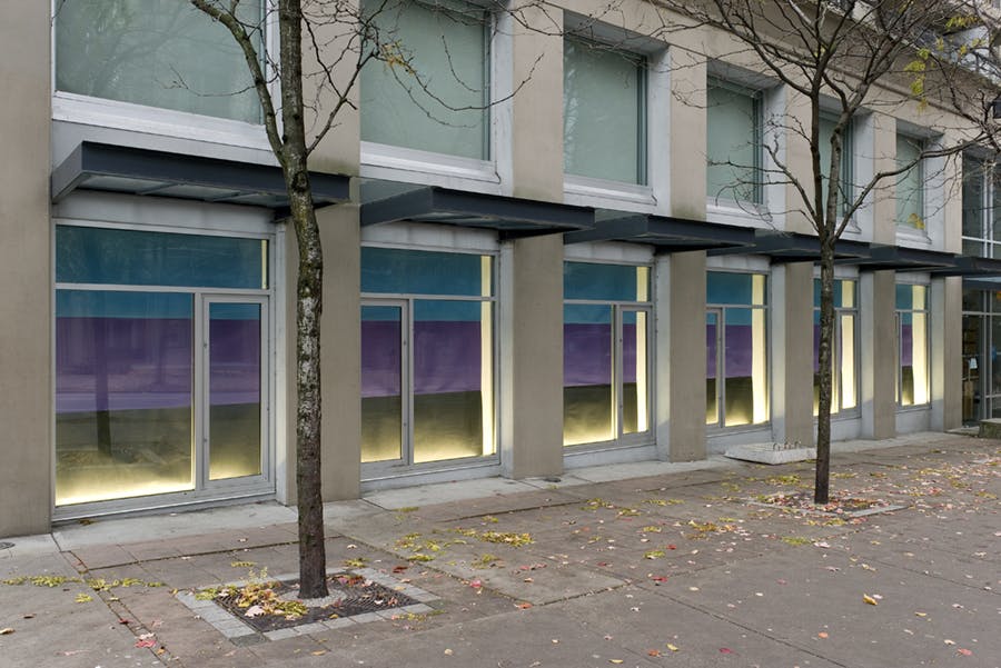 CAG’s facade windows display the work of artist Elizabeth McIntosh. Consistent across the ground floor window are three stacked stripes of blue, purple and gold.