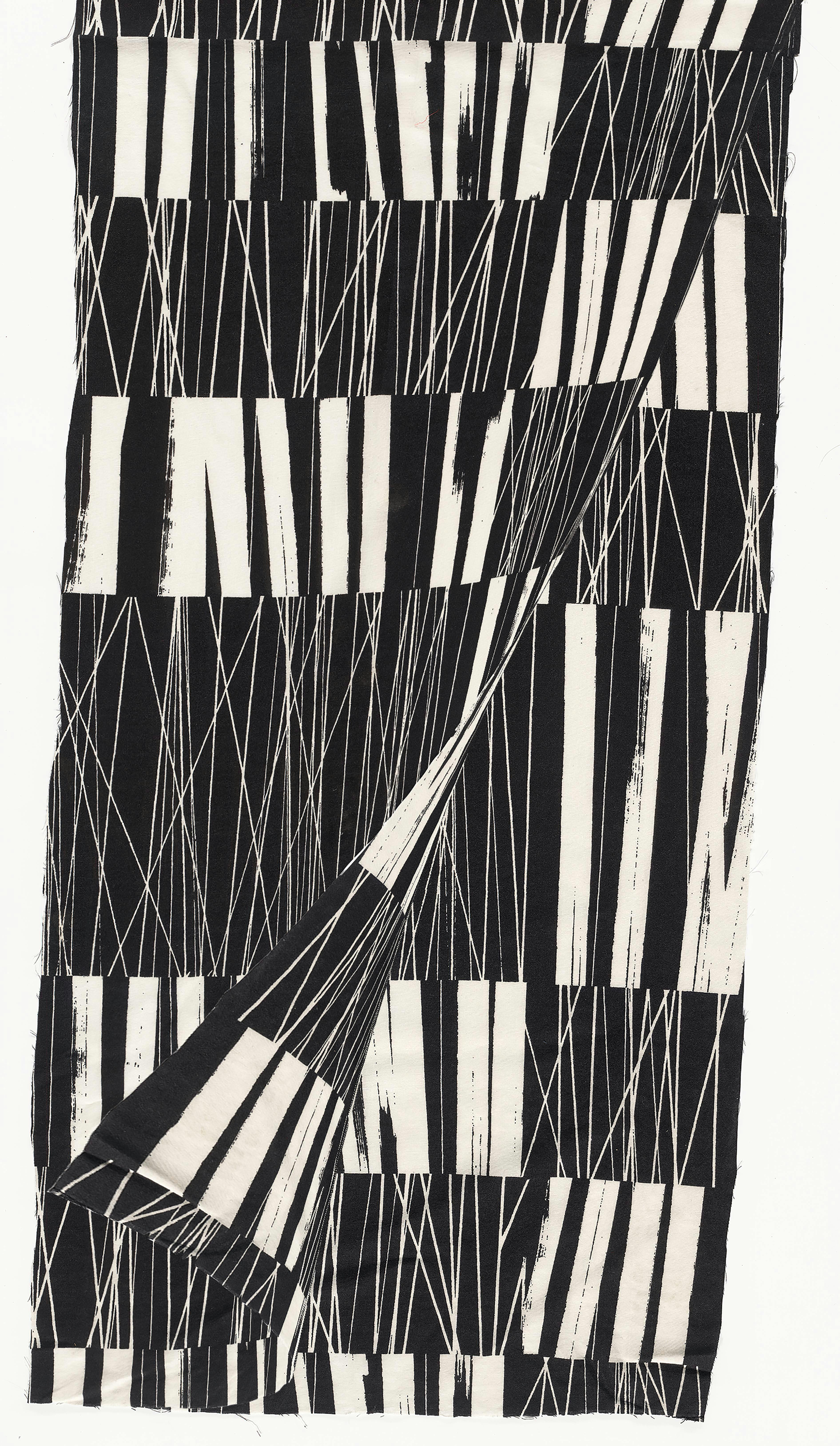 A piece of cloth with a black and white pattern made of vertical lines of varying thicknesses. The bottom right corner of the cloth is lifted up revealing the same fabric beneath it. 