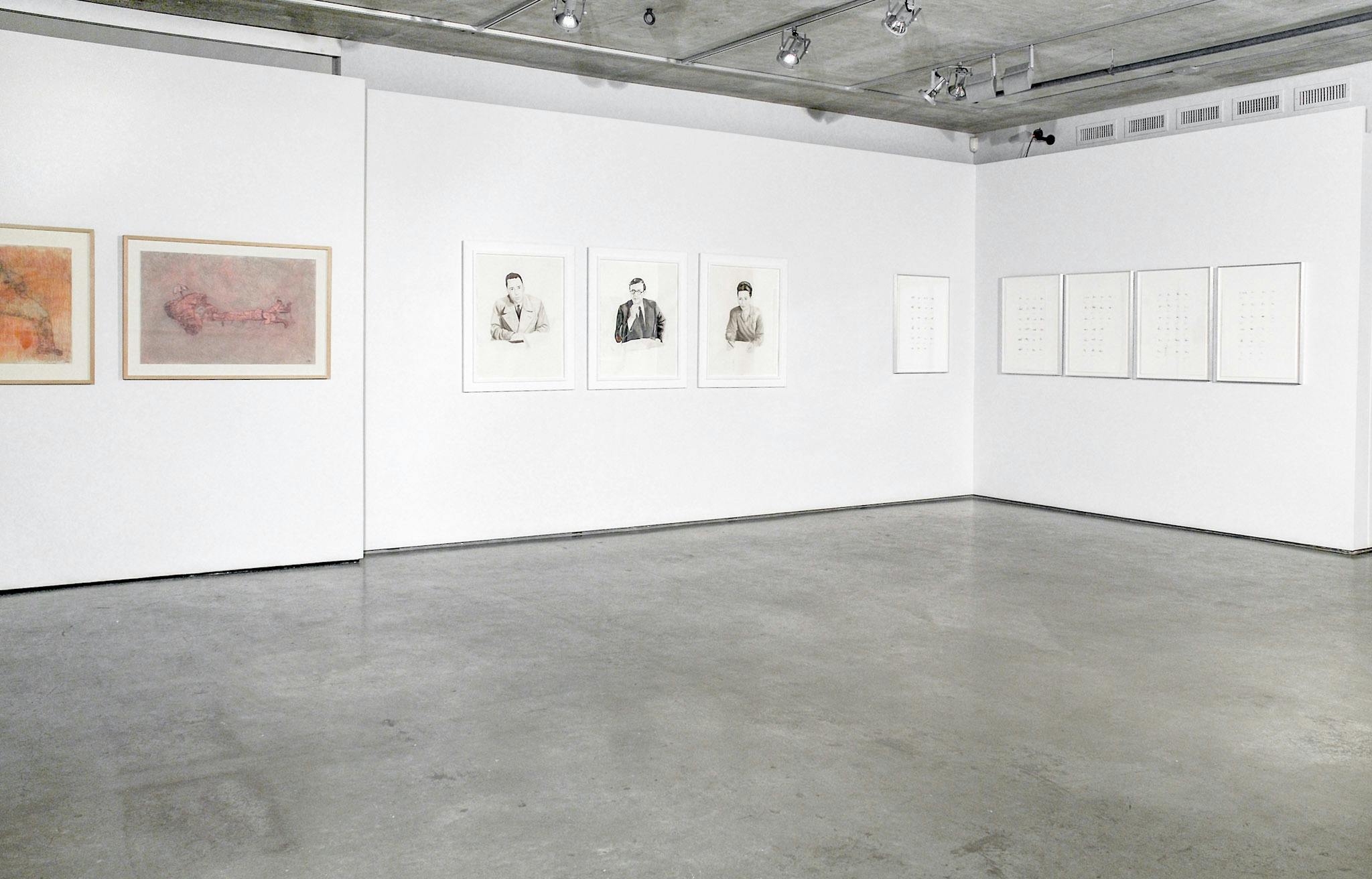 Ten drawings are mounted on the gallery walls. There is a set of three black and white portraits of people wearing suits. A set of five drawings show dots drawn on white sheets of paper. 