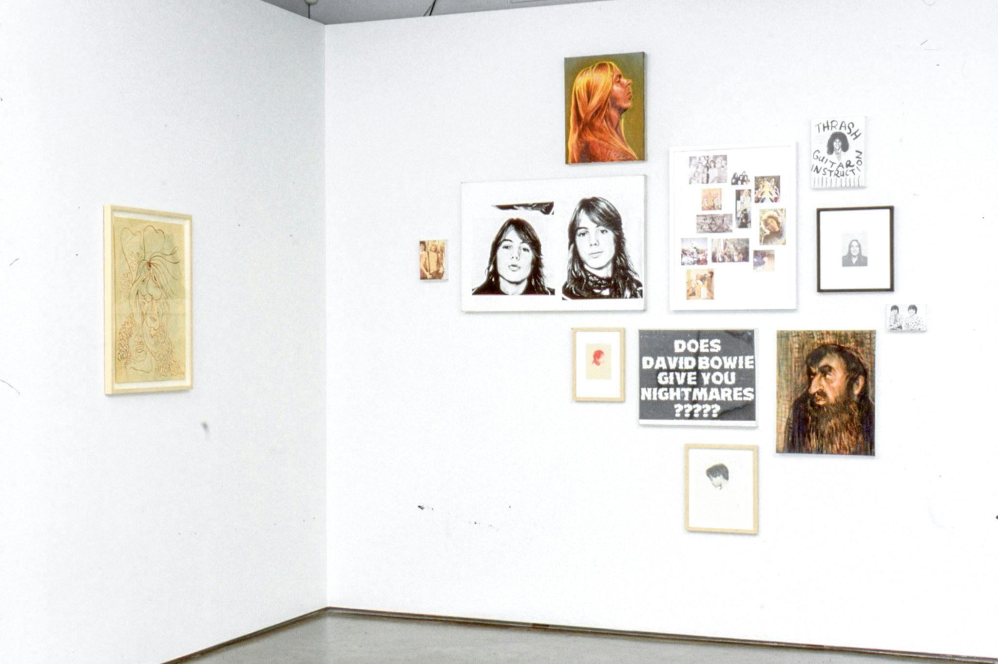 Installation image of works by Steven Shearer. Paintings, drawings, collage works, and photographs are mounted on the walls. Many of these works show figures of people, including a portrait of a person with a long brown beard.