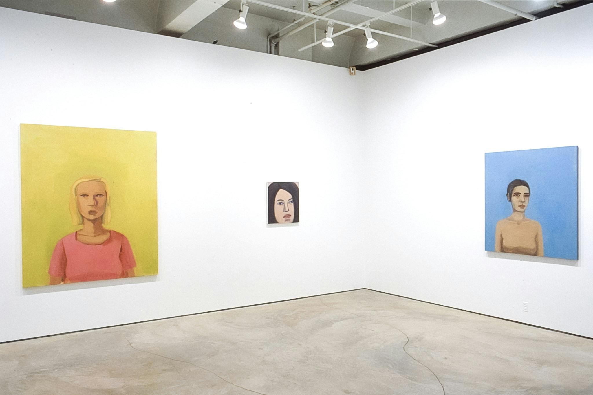 Three portrait paintings are exhibited on the galley walls. The left one is a woman in the yellow background. The middle one is a close-up of a woman’s face. The one on the right is blue. 