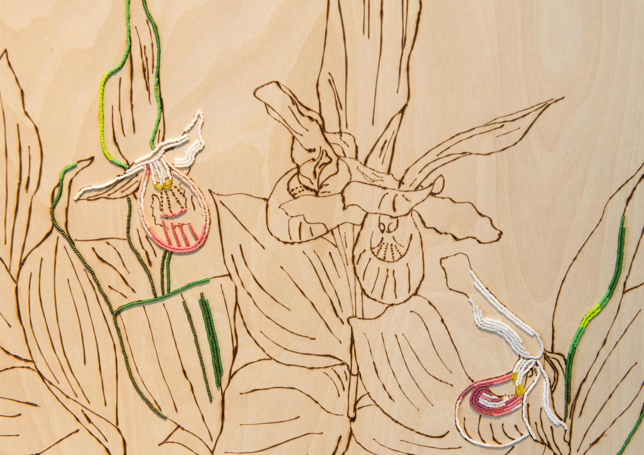 An image detail of a wood veneer panel with a rendering of flowers blooming. The rendering is composed of bead-embroidered and wood-burned lines.