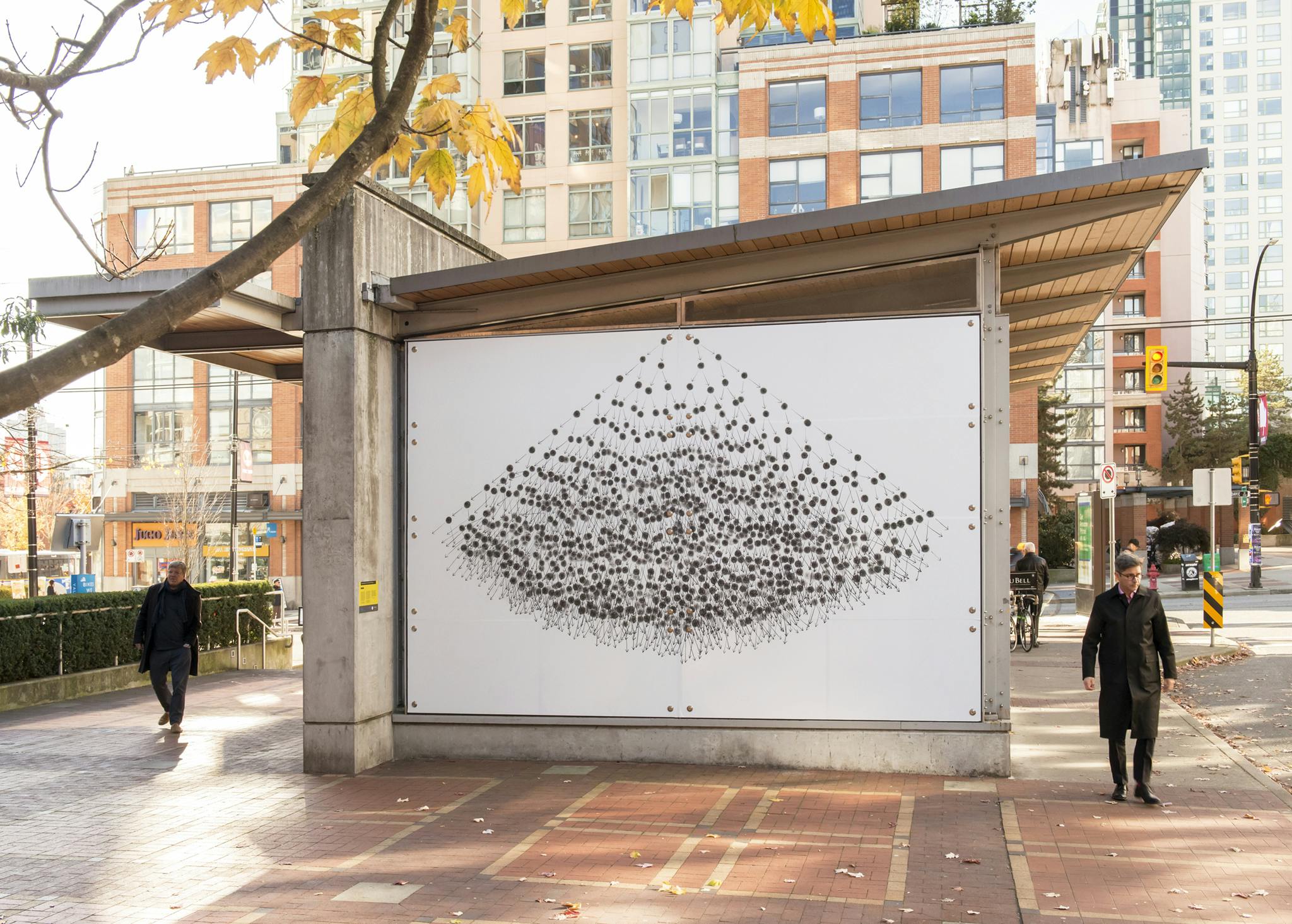 Image of Yaletown-Roundhouse Station facade with a vinyl print of a large-scale, graphite drawing affixed to its exterior; black circles form a loose, pyramid-like stack expanding down from the top. 