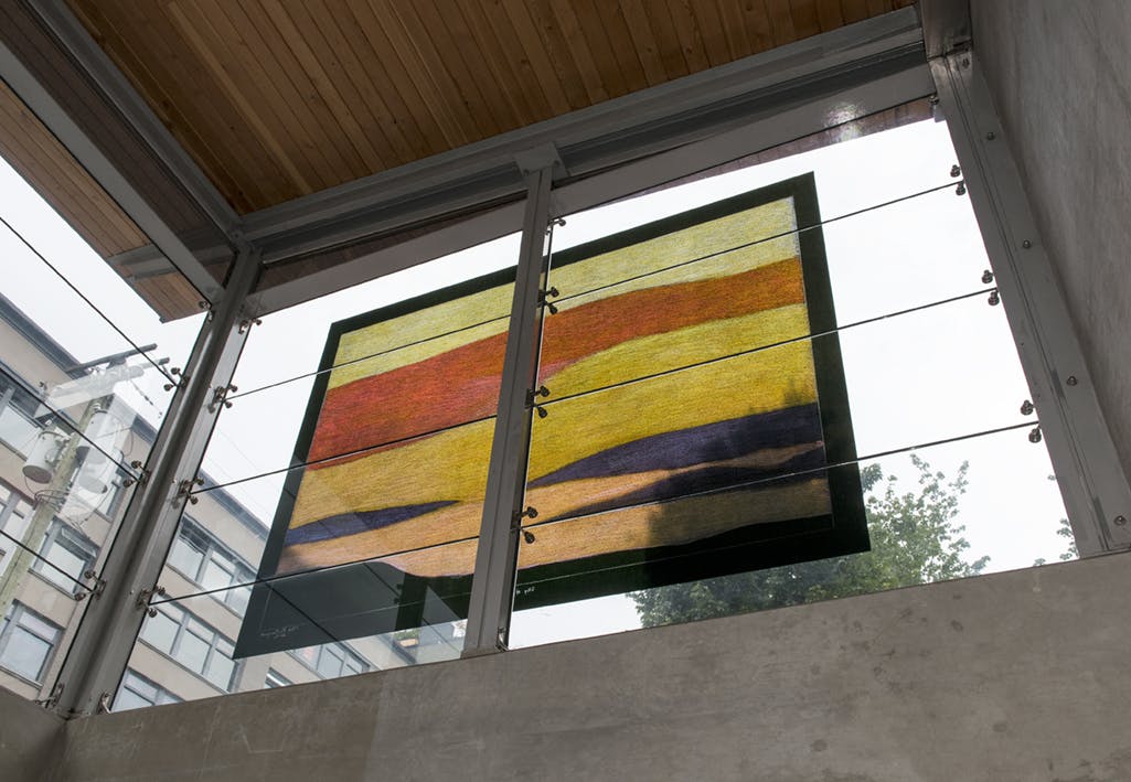 An abstract landscape drawing in vinyl by Itee Pootoogook is installed on the glass facade of Yaletown-Roundhouse station. Wavy forms resembling cloud, hill and sky formations dominate the drawing.