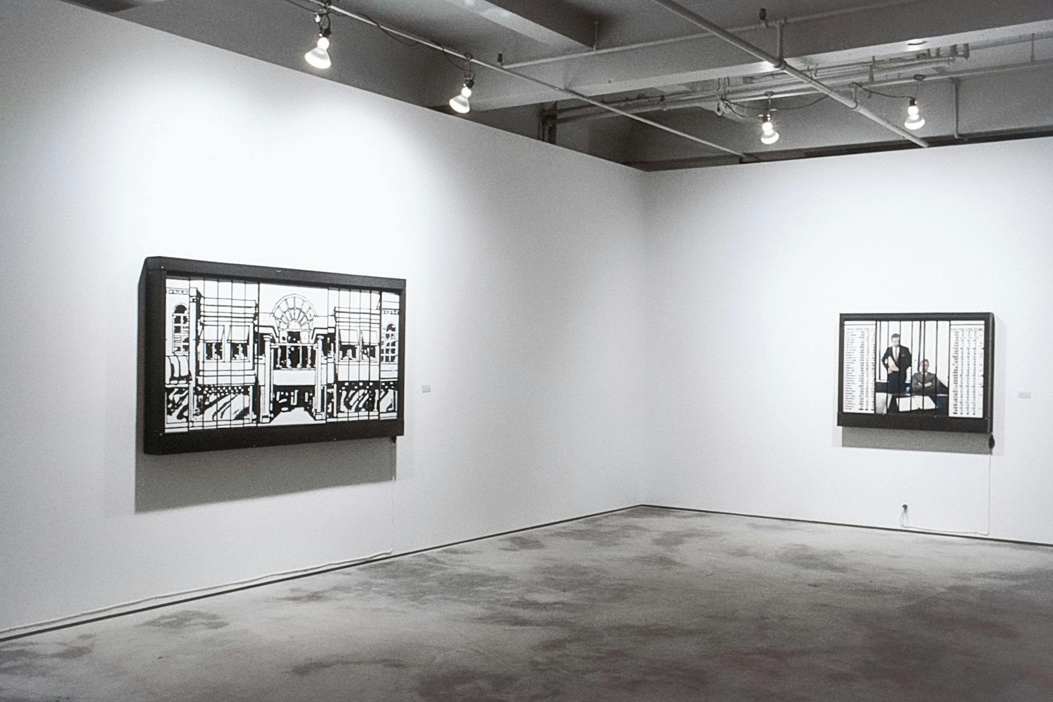 Two horizontal artworks in large black frames, in the corner of a gallery. One had two fragmented architectural drawings. The other has a fragmented picture of people in suits and datasheets.