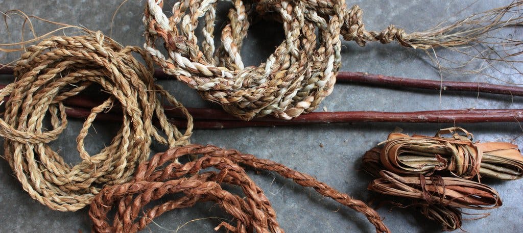 A photographic image of several roles of hemp ropes placed on a gray flat surface. 