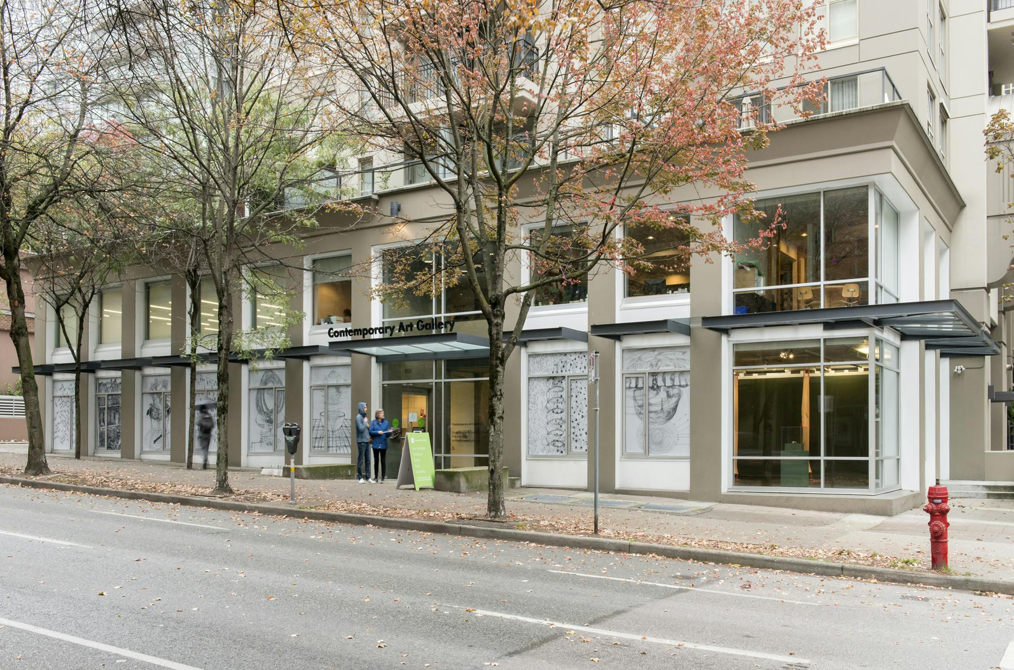 Exterior image of CAG with the work of Ingrid Koeing installed on the ground floor facade windows. Eight windows display eight, large-scale vinyl prints of back and white graphite drawings. 