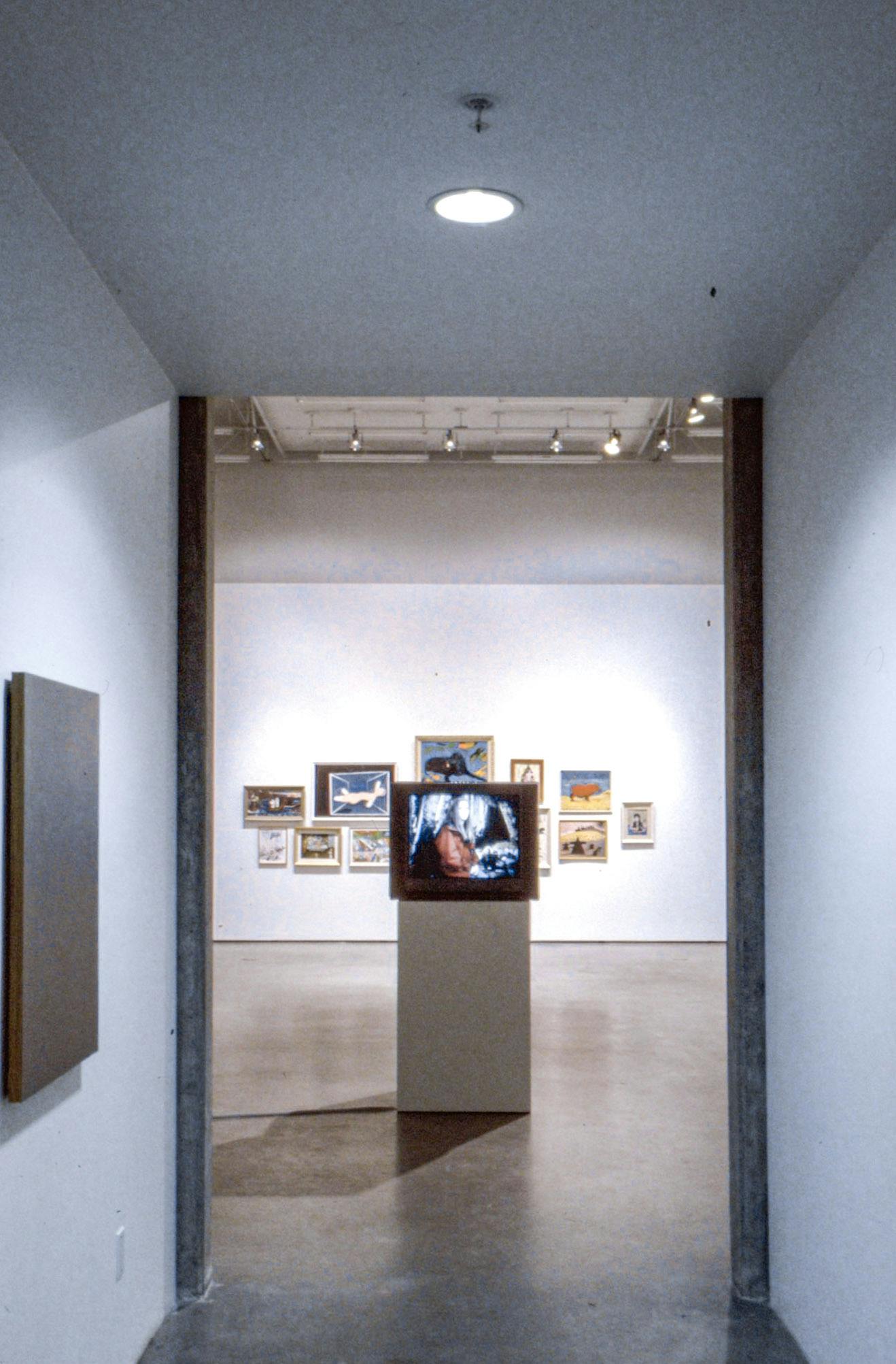 A CRT TV is placed on a pedestal installed in the middle of the gallery space. The video played on the TV shows abstract shapes. Some paintings mounted on the wall are visible behind the TV.