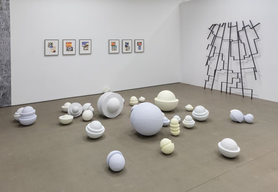 Isabel Nolan’s various sized ceramic sculptures are placed on the gallery floor. Each sculpture looks like stacked bowls, and is coloured in white, pale blue, or pale yellow. 