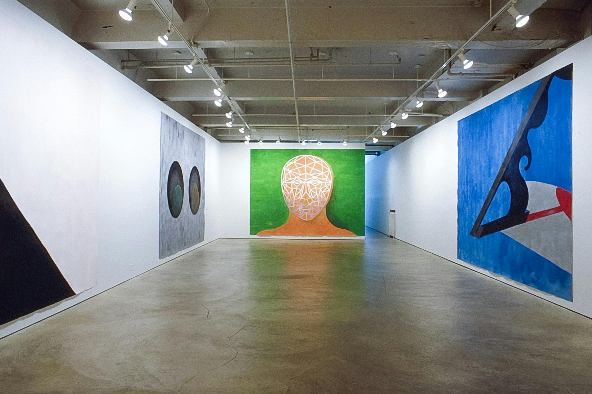 Four paintings are installed on the gallery walls. Two of them mainly depict geometric and organic shapes and lines. The one in the middle depicts a human face in the green background. 