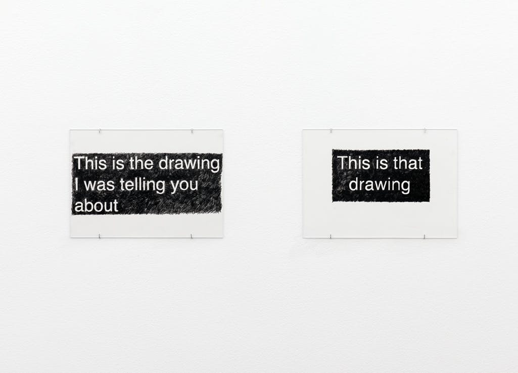 Two black and white drawings are installed on a gallery wall. A sentence, “This is the drawing I was telling you about” is written on one, and “This is that drawing” is written on the other. 