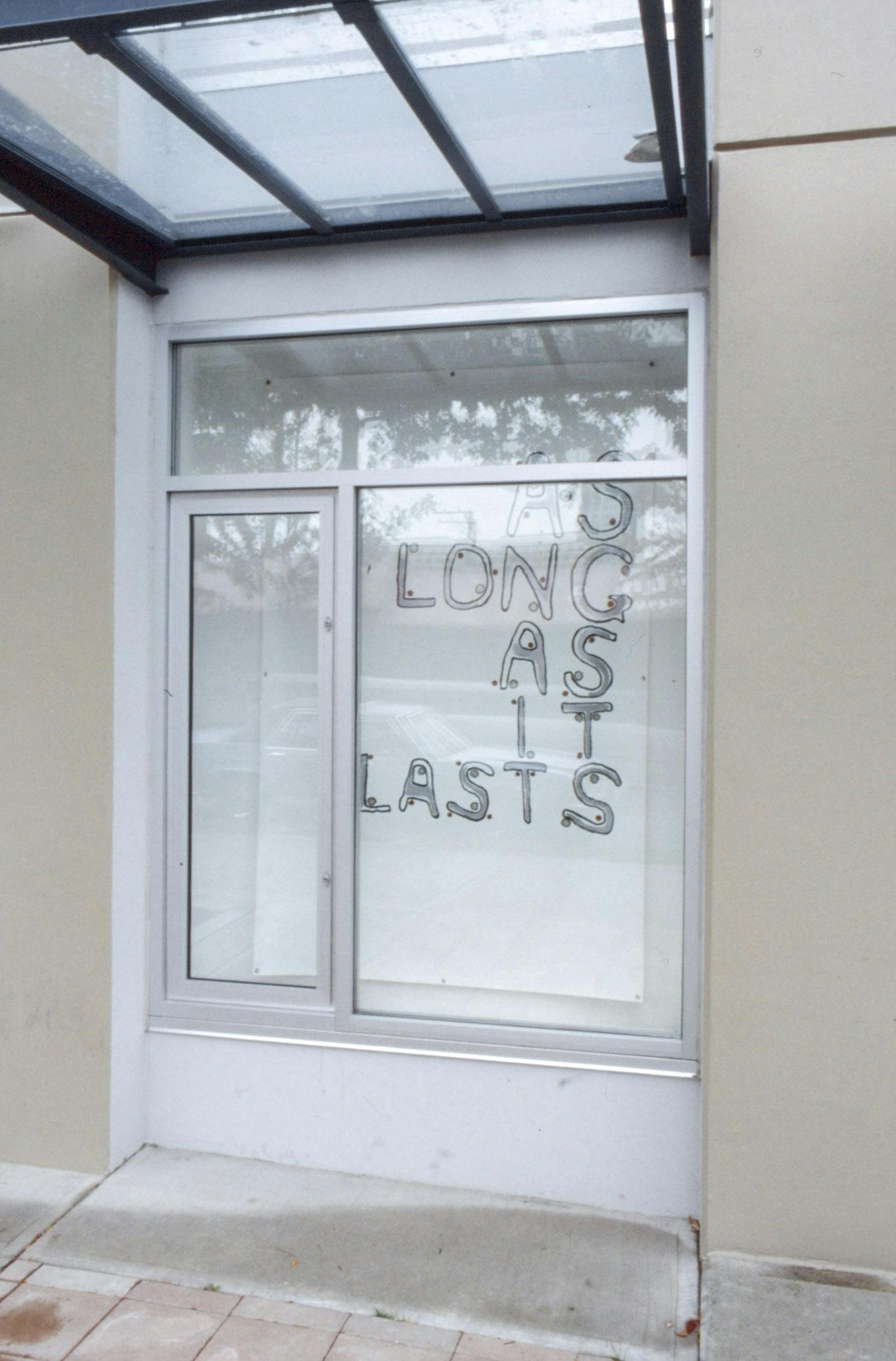 Jill Henderson’s text-based work is installed in one of CAG’s window spaces. The window in this image showcases a handwritten text that reads “as long as it lasts” all in upper cases. 
