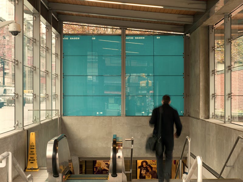 Scott Massey’s two-dimensional work covers the window above the entrance of Yaletown-Roundhouse Station. The installed picture shows white stars in a robin egg blue background. 