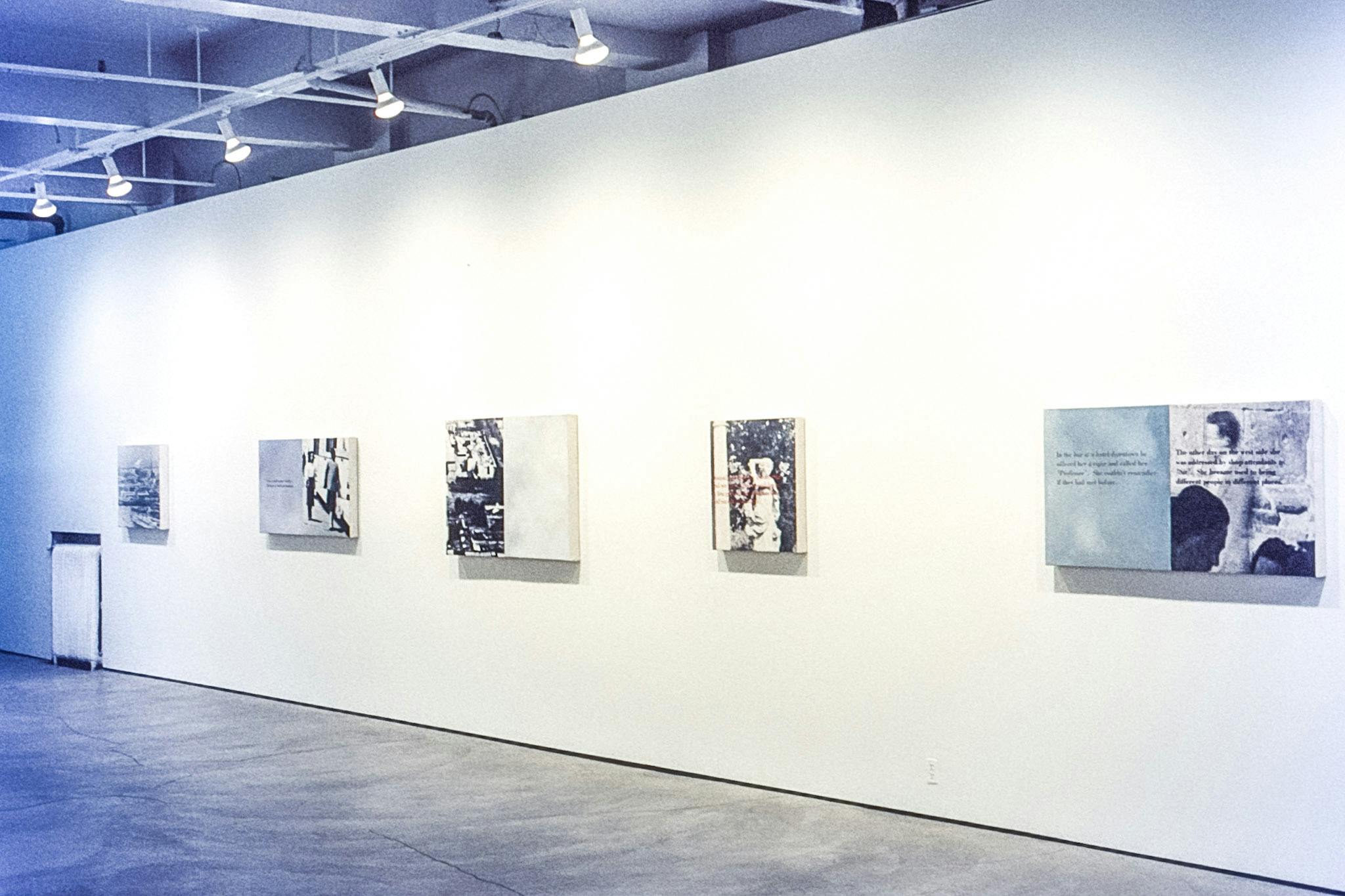 Five artworks mounted on the gallery wall. Each of them has a black and white photograph of people or a cityscape accompanied by texts, either in black or red, written beside or over the photograph.