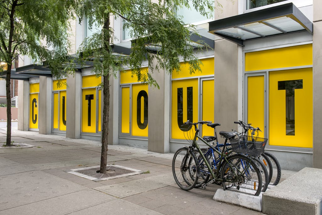 Kay Rosen’s text-based work installed on CAG’s exterior facade. Yellow vinyl sheets cover the windows. In each window, a letter from the word “CUTOUT” has been excised from the vinyl.
