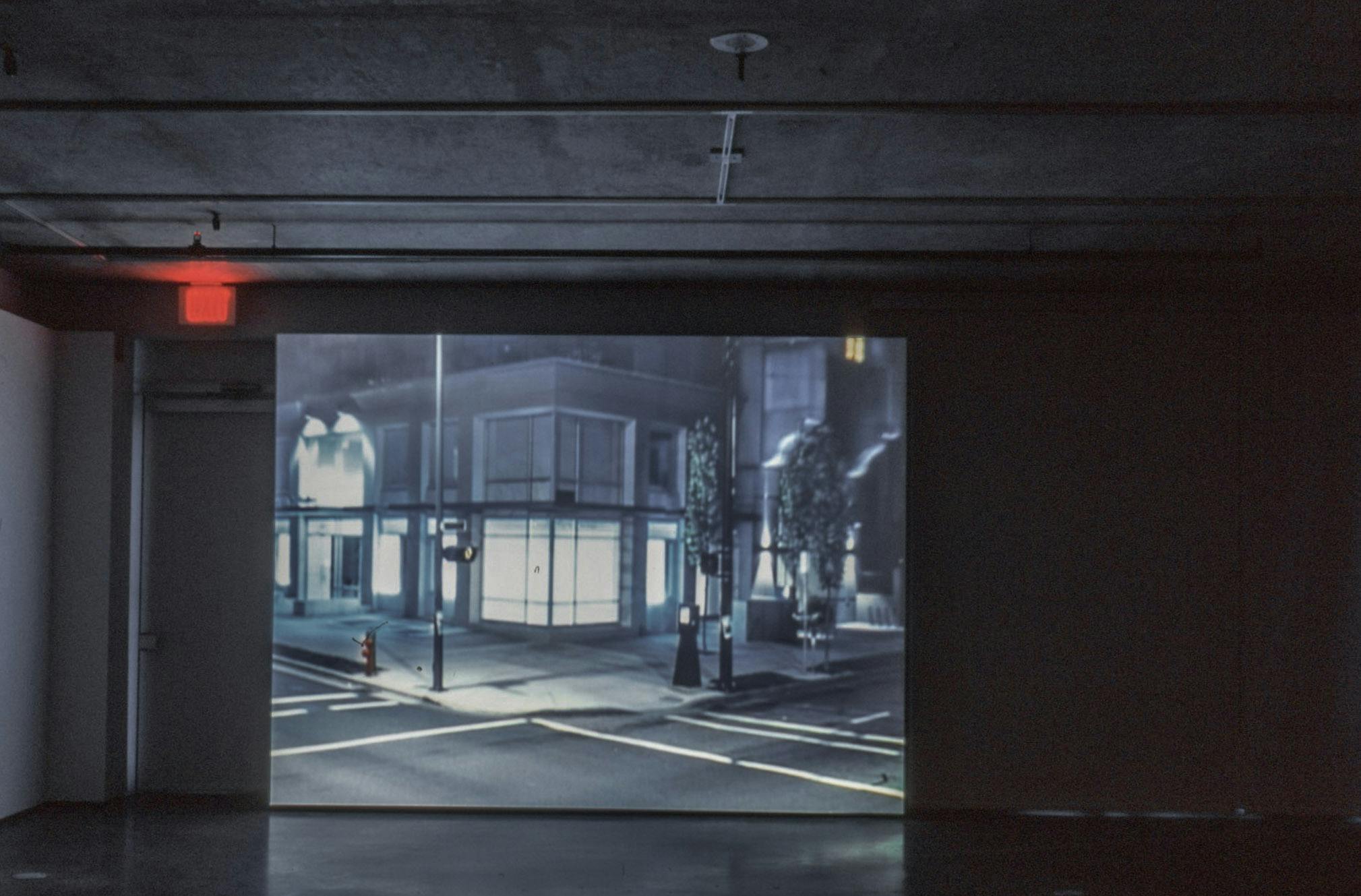 This is a video work projected on a screen installed in a darkened gallery. The screen shows the illuminated exterior of the CAG building during the night. 